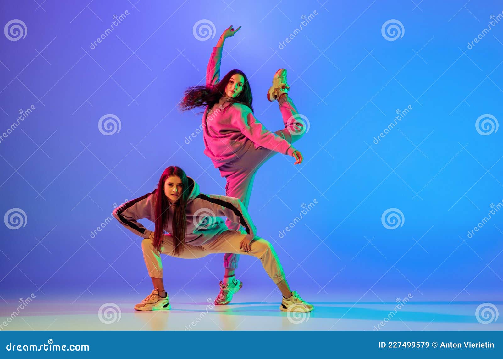 Dos Jóvenes Bellas Con Ropa Casual Bailando Hiphop De Balanceo Sobre Fondo Azul En Luz De Neón. Imagen de archivo - Imagen de brillante, movimiento: 227499579