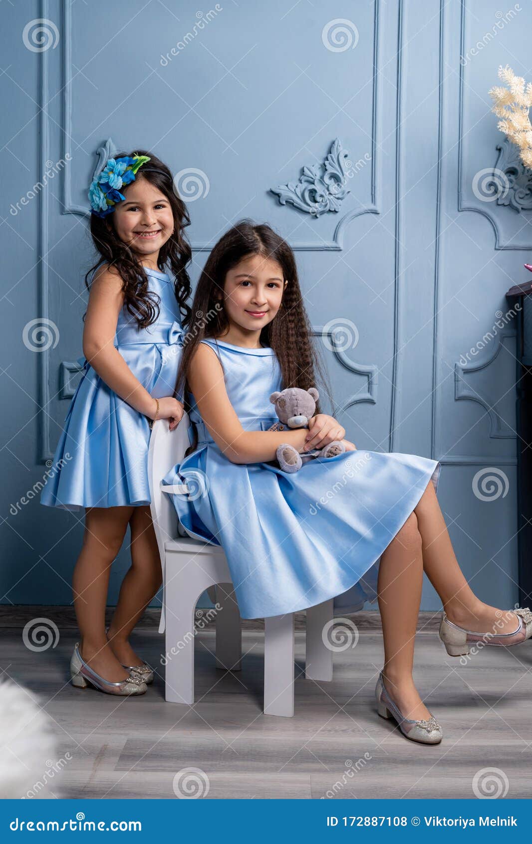 Dos Niños Con Vestidos Azules, Zapatos Beige Sobre Los Talones En Un Fondo Gris Foto de archivo - de ropa, alegre: 172887108