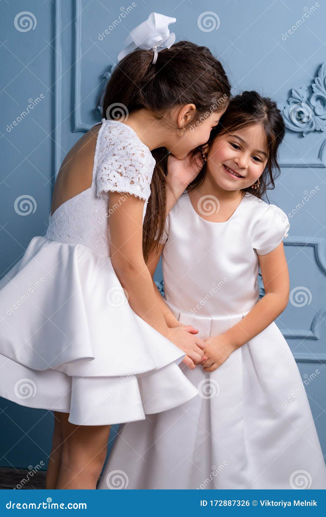 Dos Niños Susurrando Vestidos En Un Fondo Gris Foto de - Imagen de pendientes, familia: 172887326