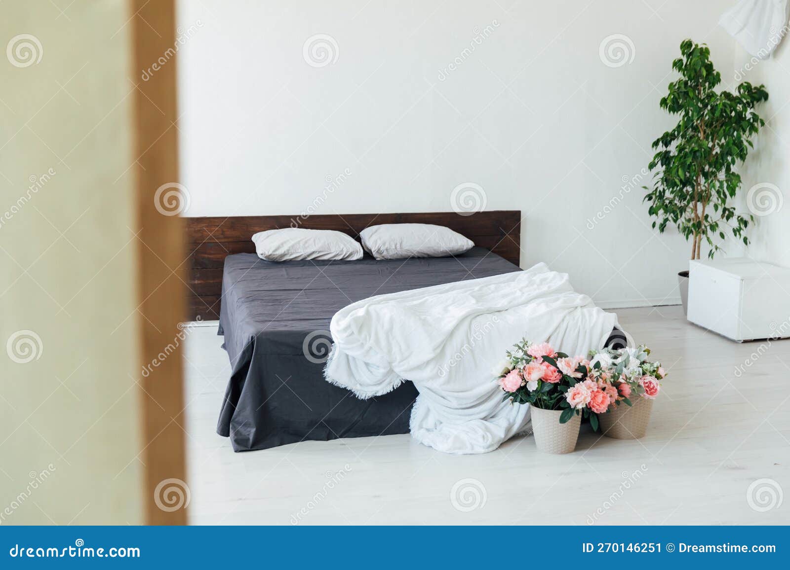 Double Bed with Black White Bedspread Stands in the Room with Flowers