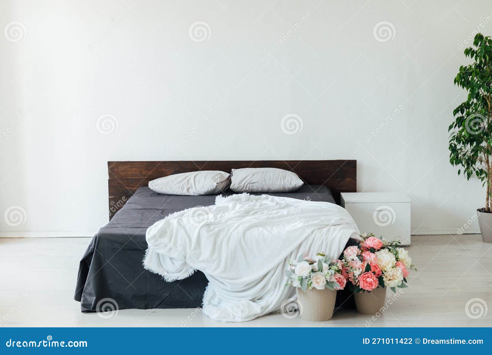 Double Bed with Black White Bedspread Stands in the Room with Flowers