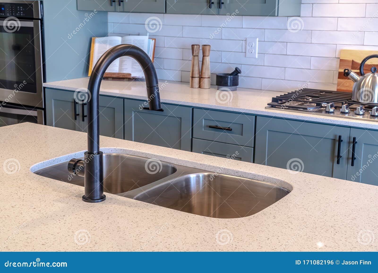 Double Bowl Sink and Black Faucet on Kitchen Island Against Cooktop and ...