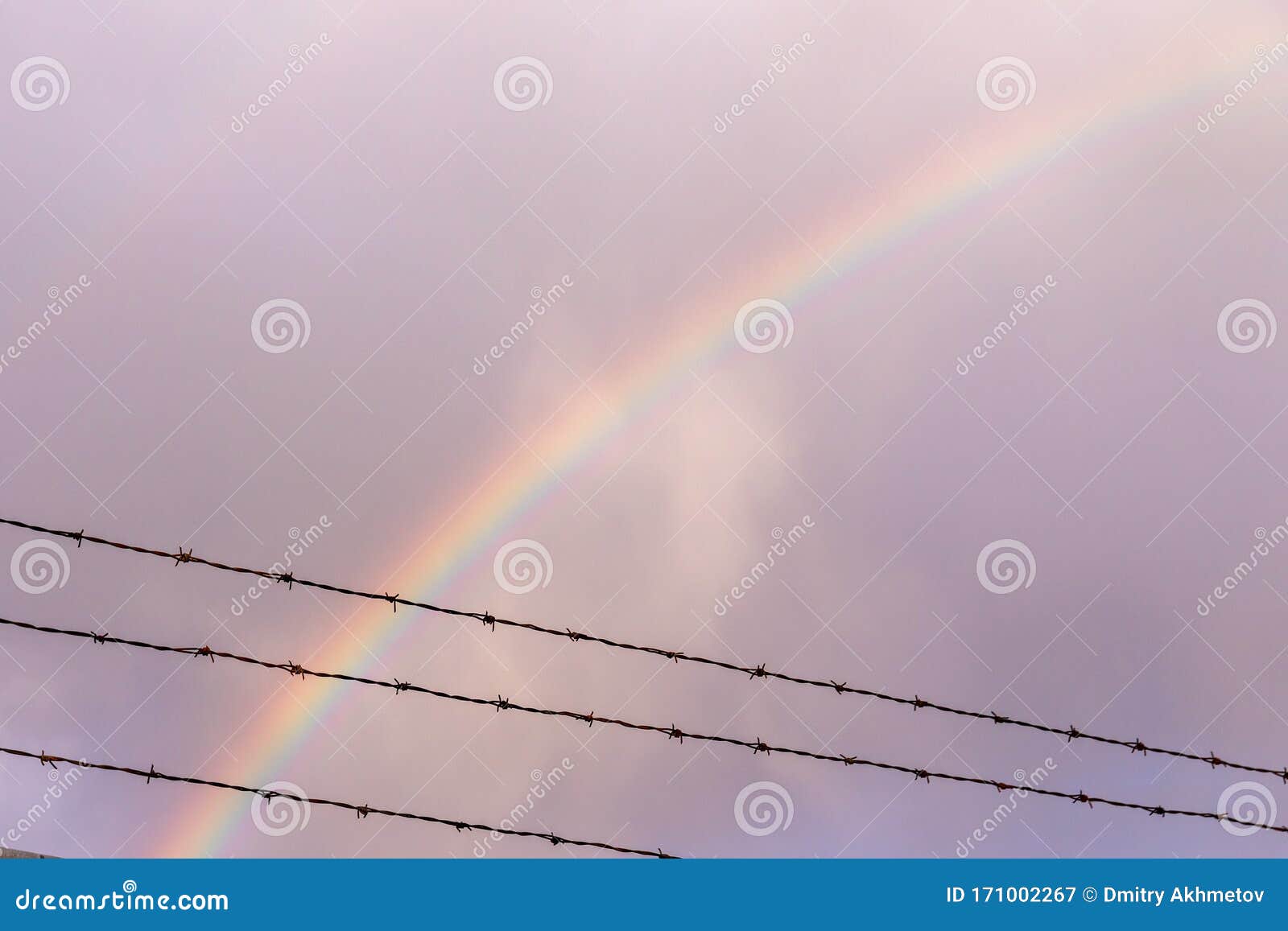 double rainbow behind rows of a barbed wire