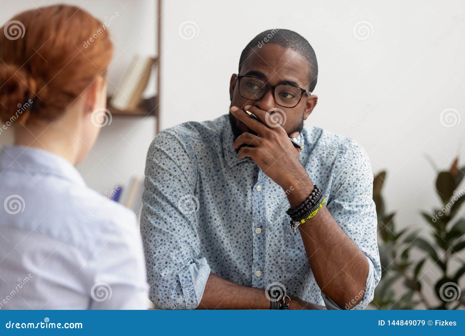 doubtful african hr talking to caucasian applicant at job interview