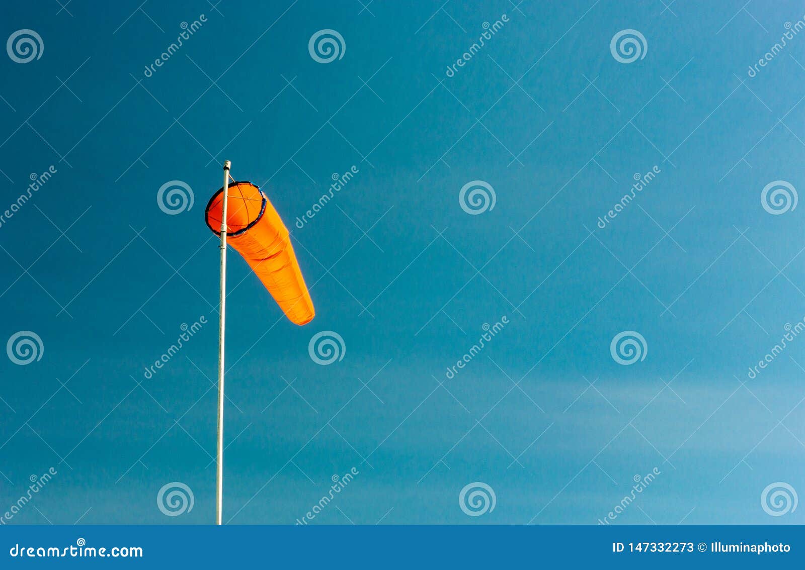 Downward Angled Plain Orange Windsock Against a Clear Blue Sky. Stock