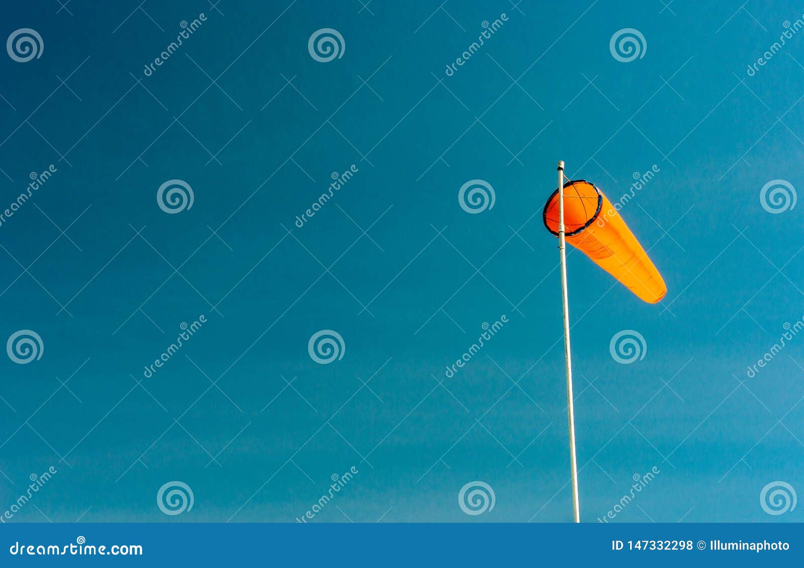 Downward Angled Plain Orange Windsock Against a Clear Blue Sky. Stock