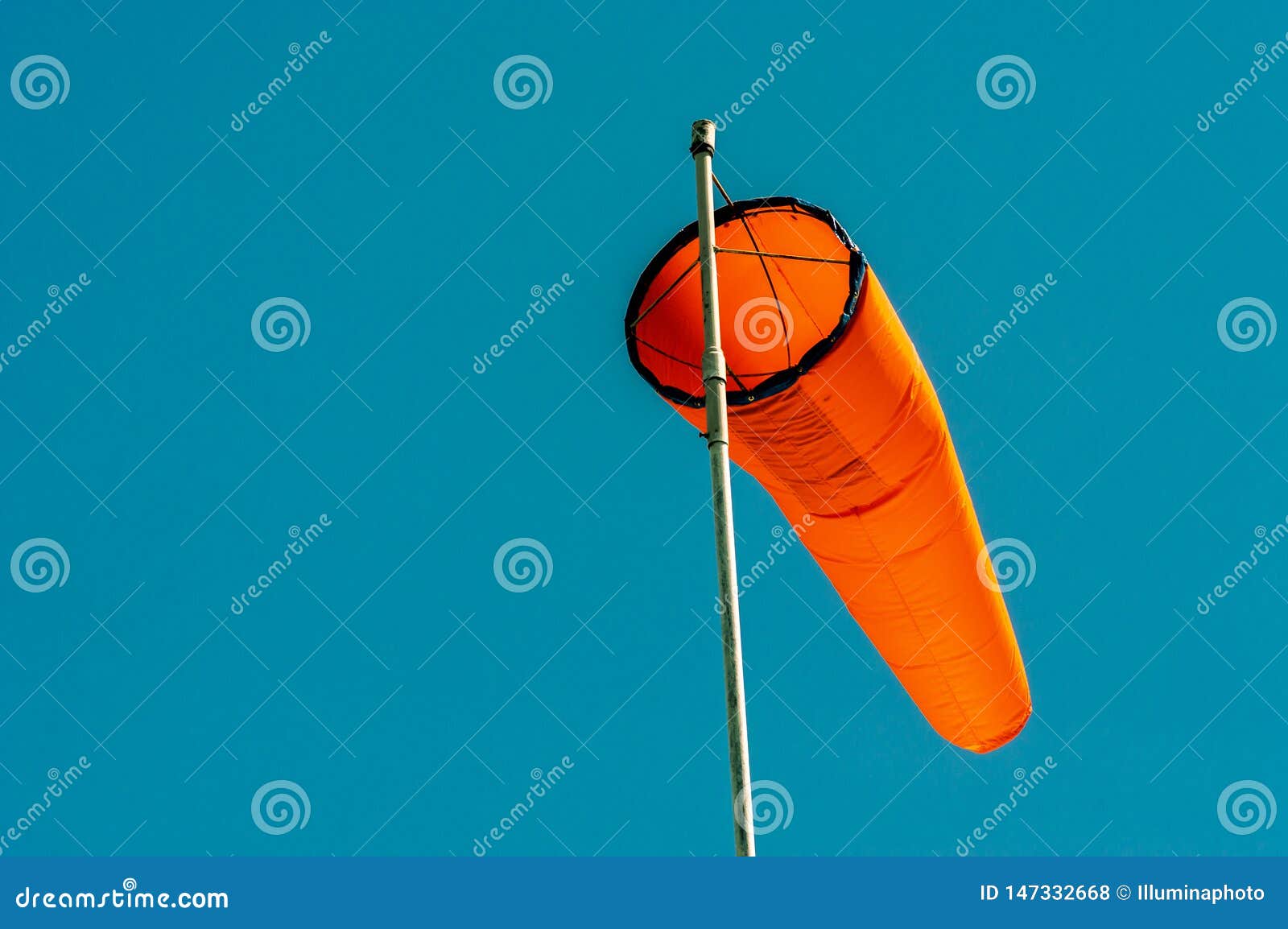 Downward Angled Plain Orange Windsock Against a Clear Blue Sky. Stock
