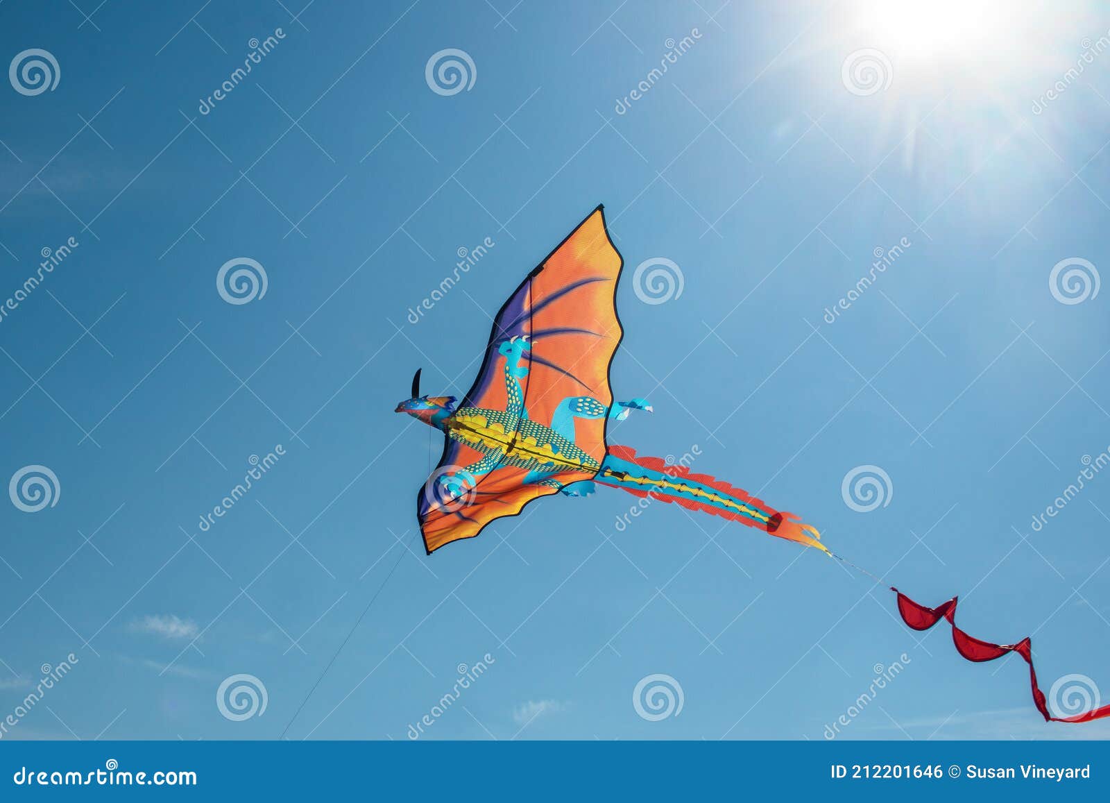 Dragon Kite Flying in Blue Sky with Sun Rays in Sky Above it Stock