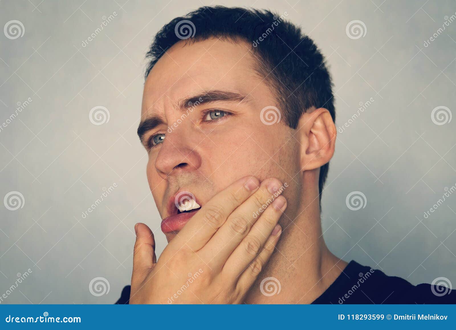 dramatic shot of a man in pain holding his jaw. toothache. a punch in the jaw slap. insult. the guy strokes his chin after shaving