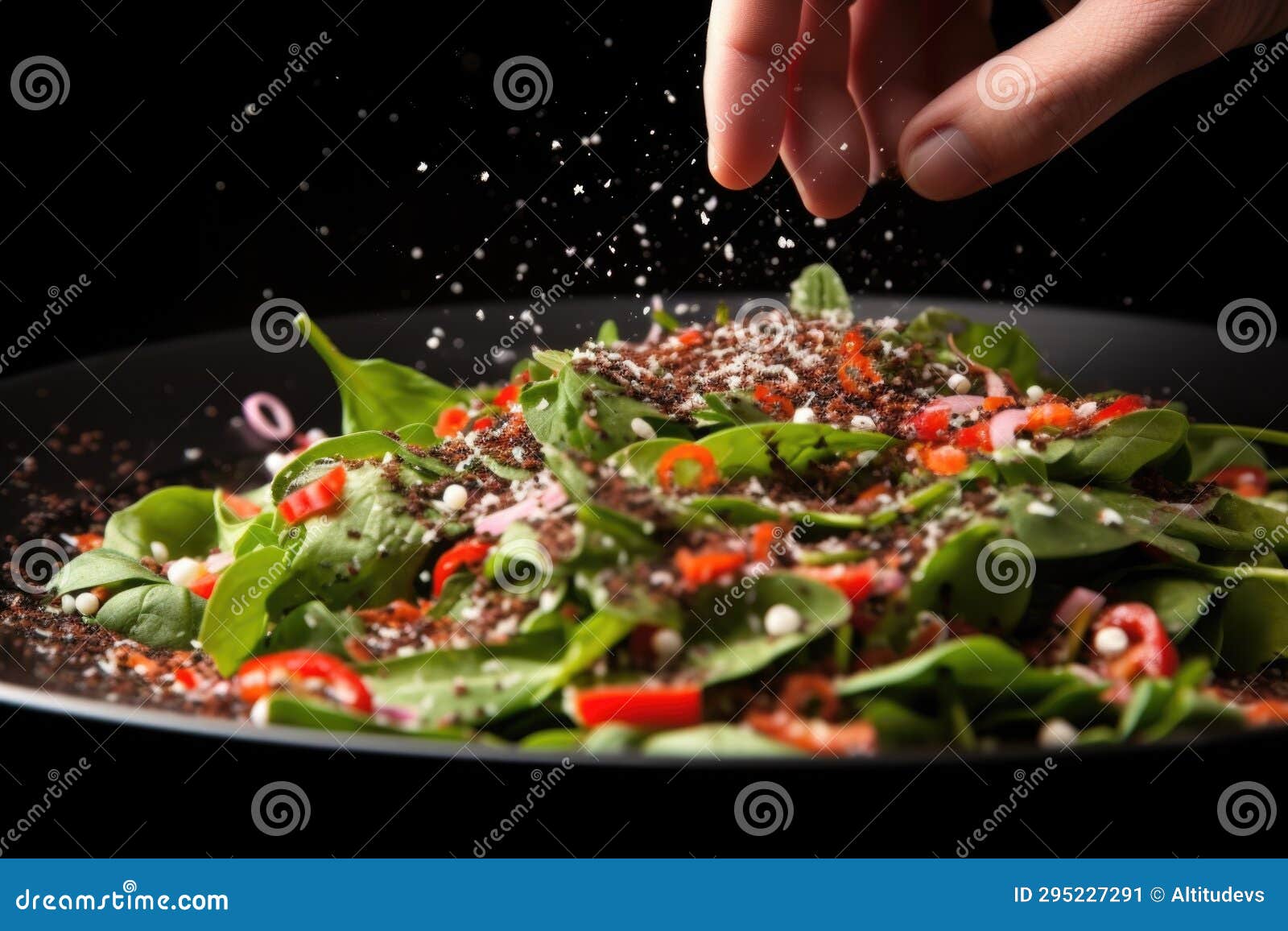 Dramatic Sprinkle of Black Pepper on Salad by a Hand Stock Image