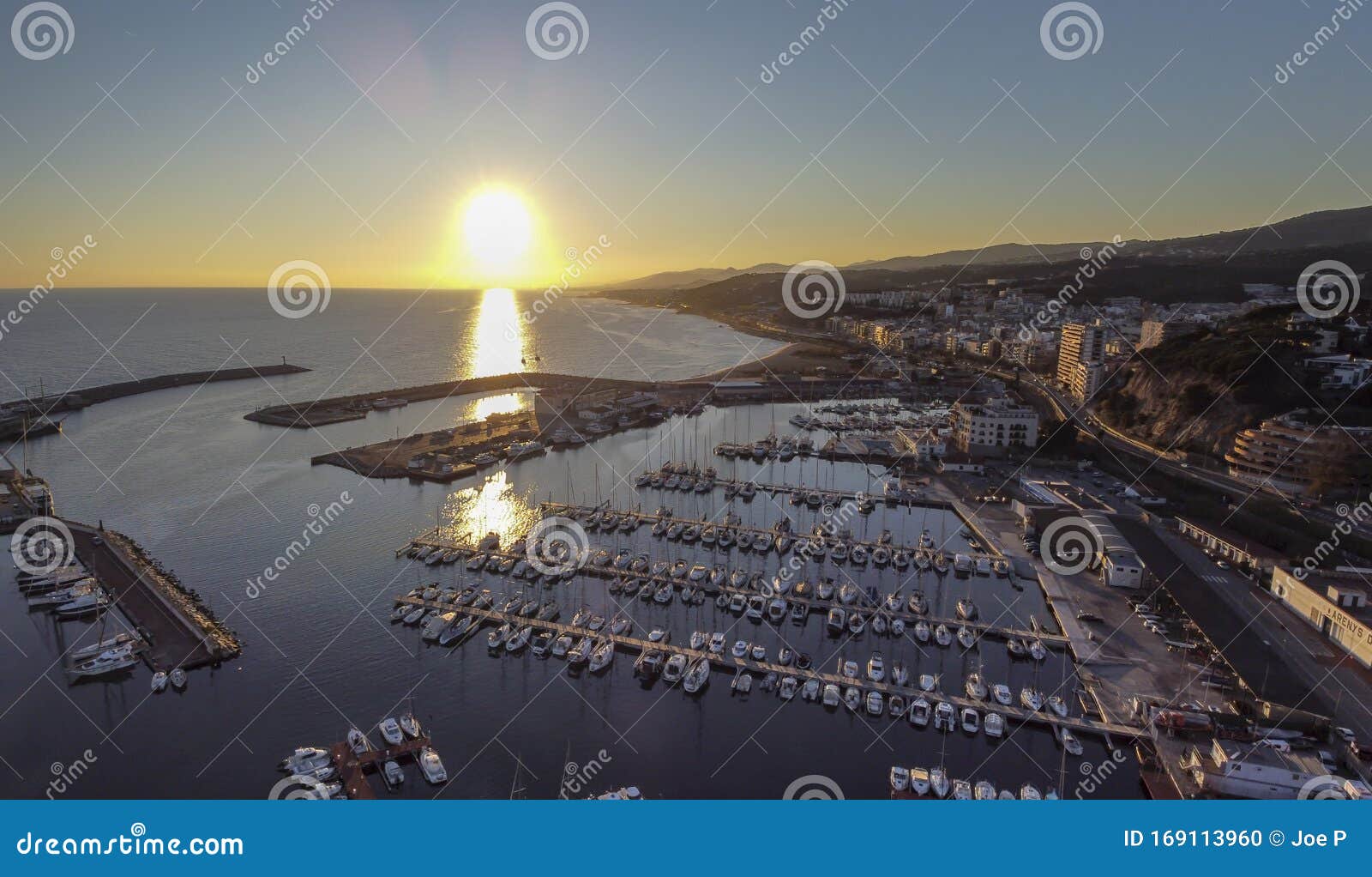 dramatic sunset over the mediterranean sea in el maresme coast. aerial panoramic view of arenys de mar harbor at dawn
