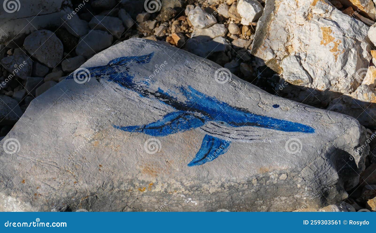drawing of a whale on a stone by the sea