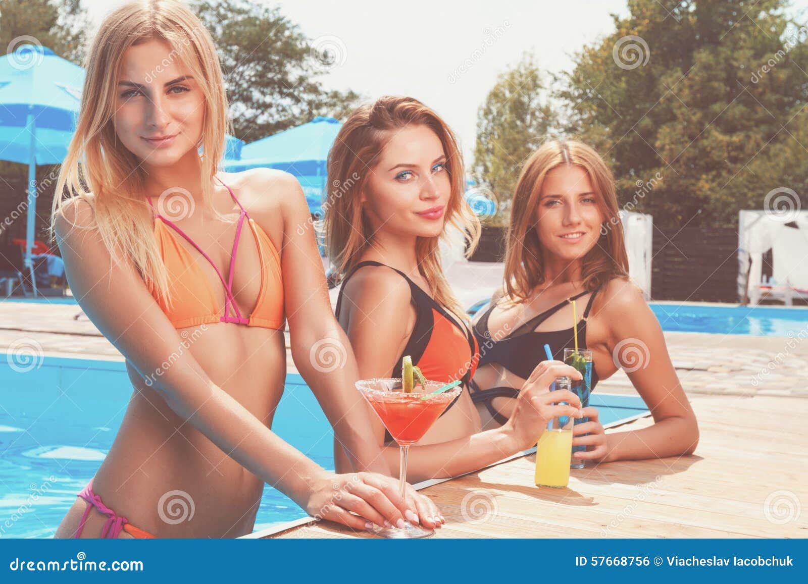 Подружки в купальниках веселятся около бассейна