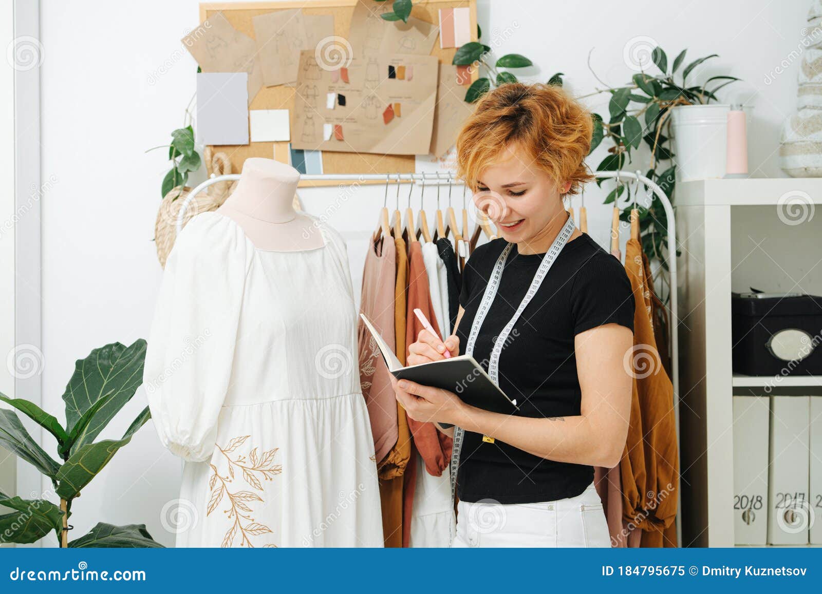 Dressmaker in a Workshop Writes in Notepad, she is Working on a New ...