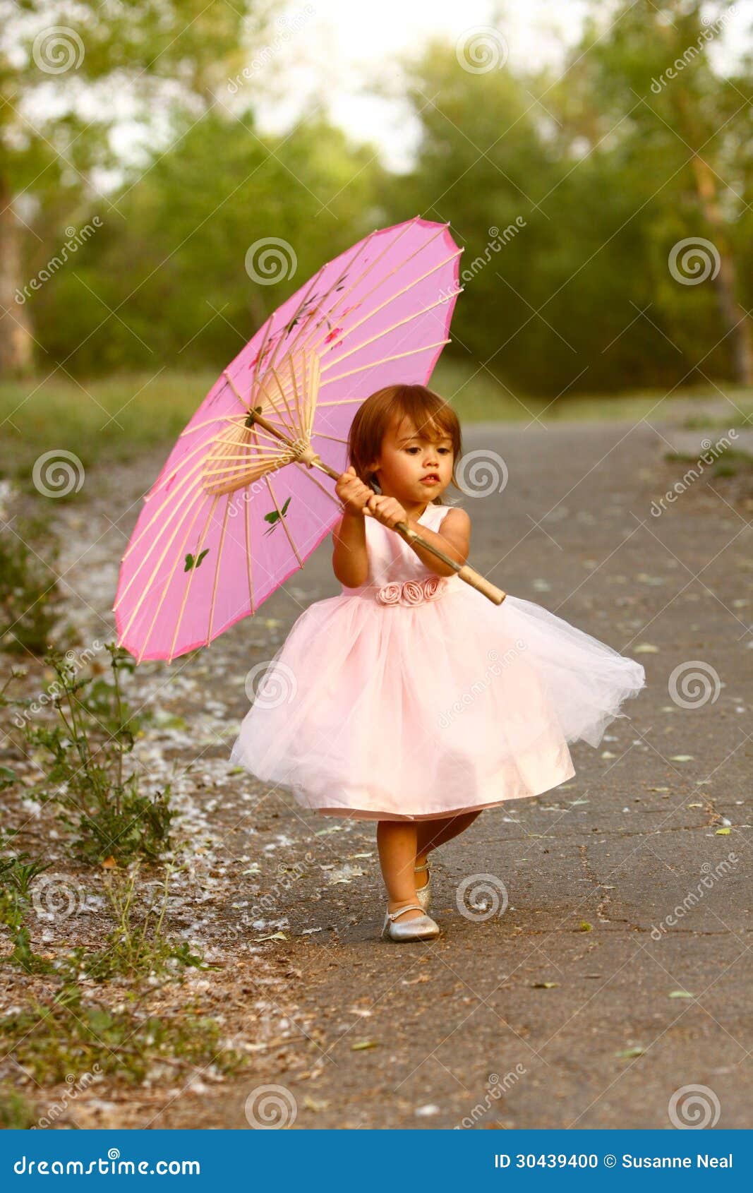 dressy two-year-old girl carrying pink parasol