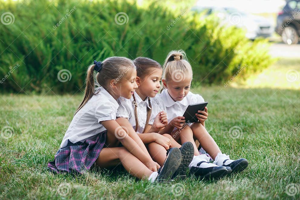 Drie Meisjes Zitten Op Het Gras En Lezen Een Ebook Leerlingen Van Lage School Begin Van Lessen 