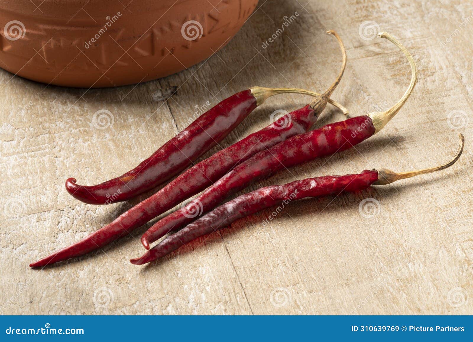 dried raw mexican chile de arbol peppers on wooden background