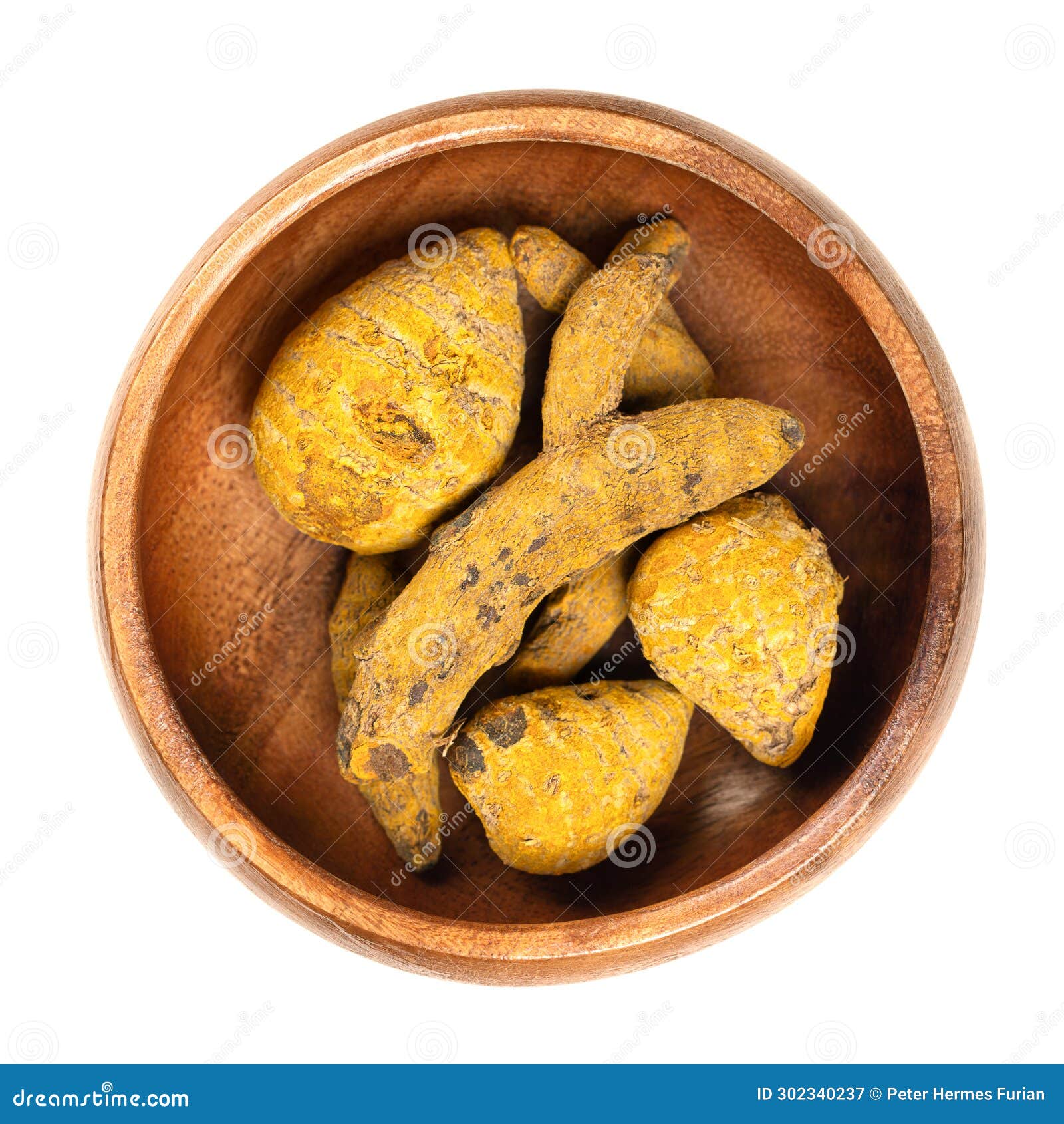 dried whole turmeric root, dehydrated rhizomes in a wooden bowl