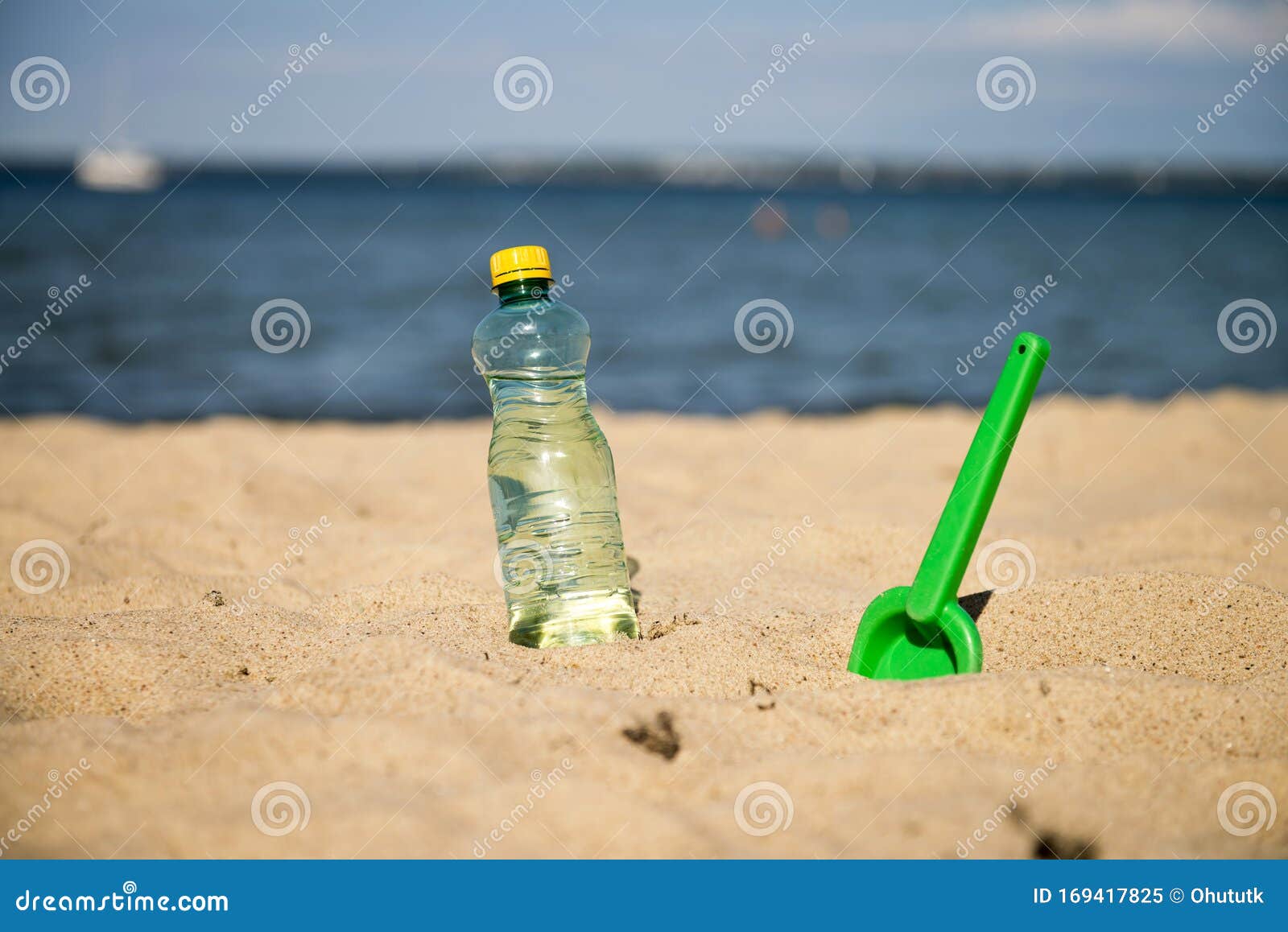 Plastic Bottle of Fresh Water is on the Sand by the Sea. Drinking Water