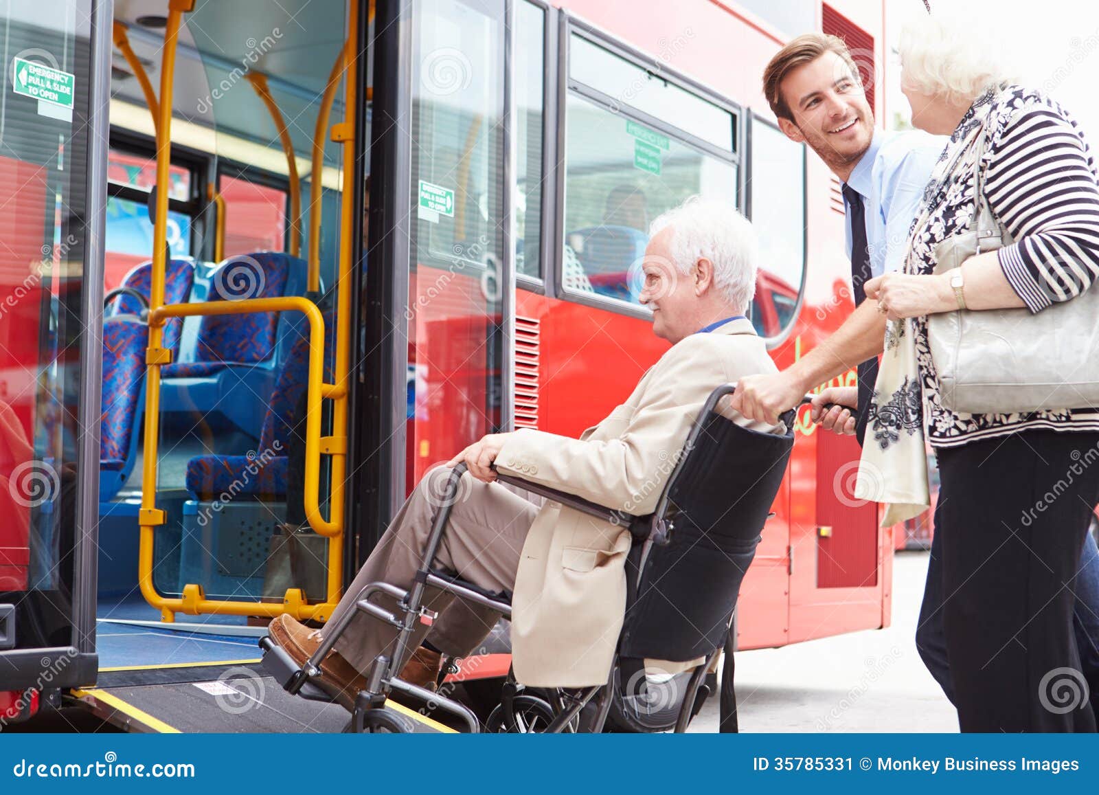 driver helping senior couple board bus via wheelchair ramp