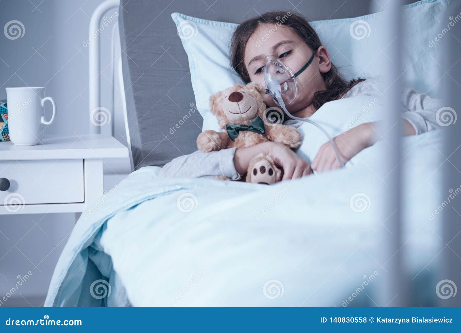 Droevig jong geitje met blaasbindweefselvermeerdering die in een het ziekenhuisbed liggen met zuurstofmasker en pluchestuk speelgoed, echt fotoconcept