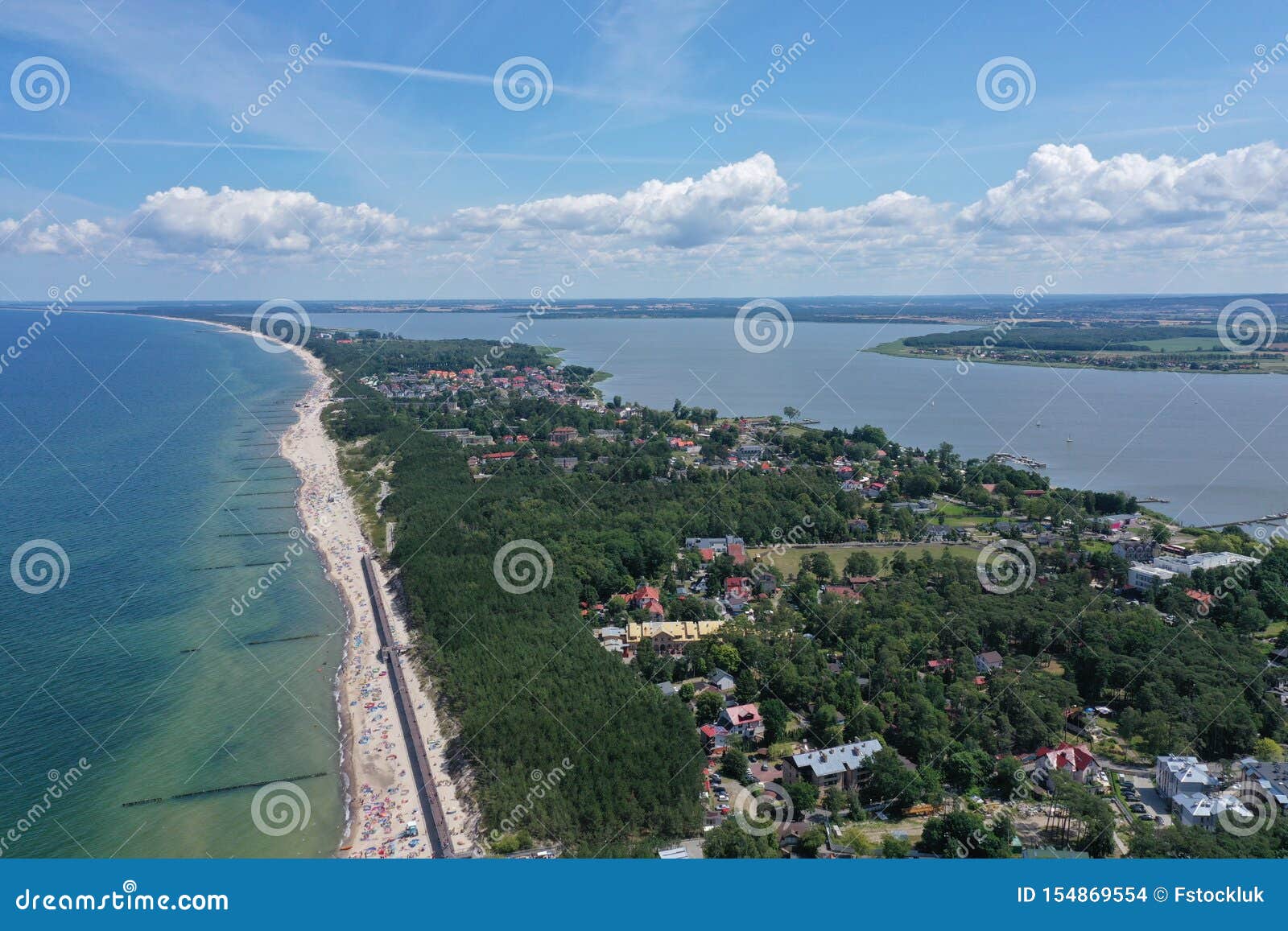 drone aerial perspective view on touristic city located on narrow spit between sea and lake with sunbathers on sand beach