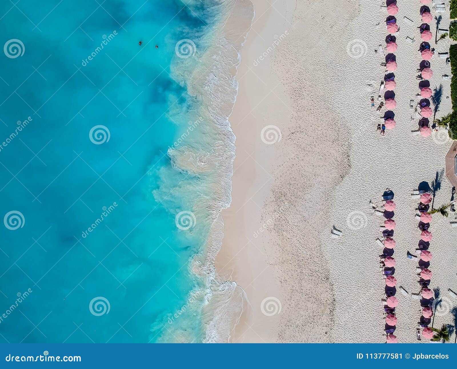 drone photo of beach with red umbrellas in grace bay, providenciales, turks and caicos