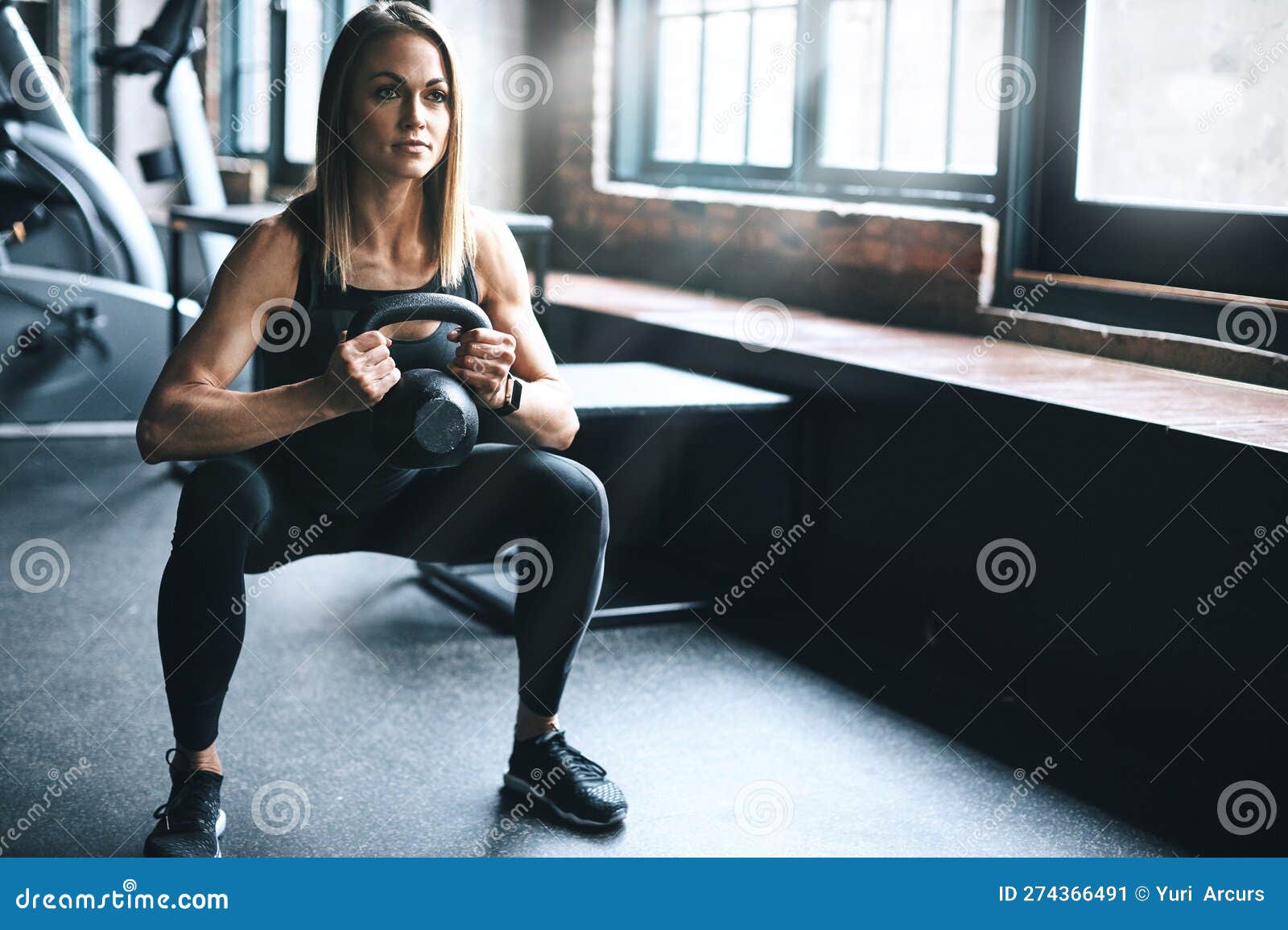 Drop it Down Low. a Young Woman Working Out with a Kettle Bell in a Gym ...