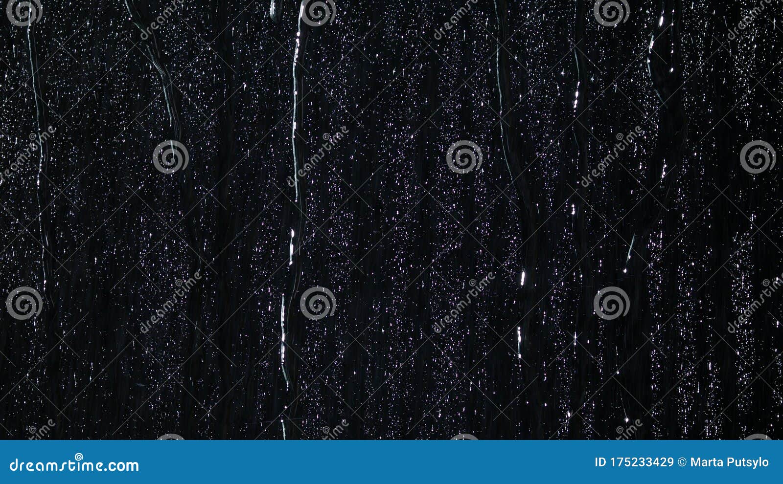 droplets of water on black glass running down.