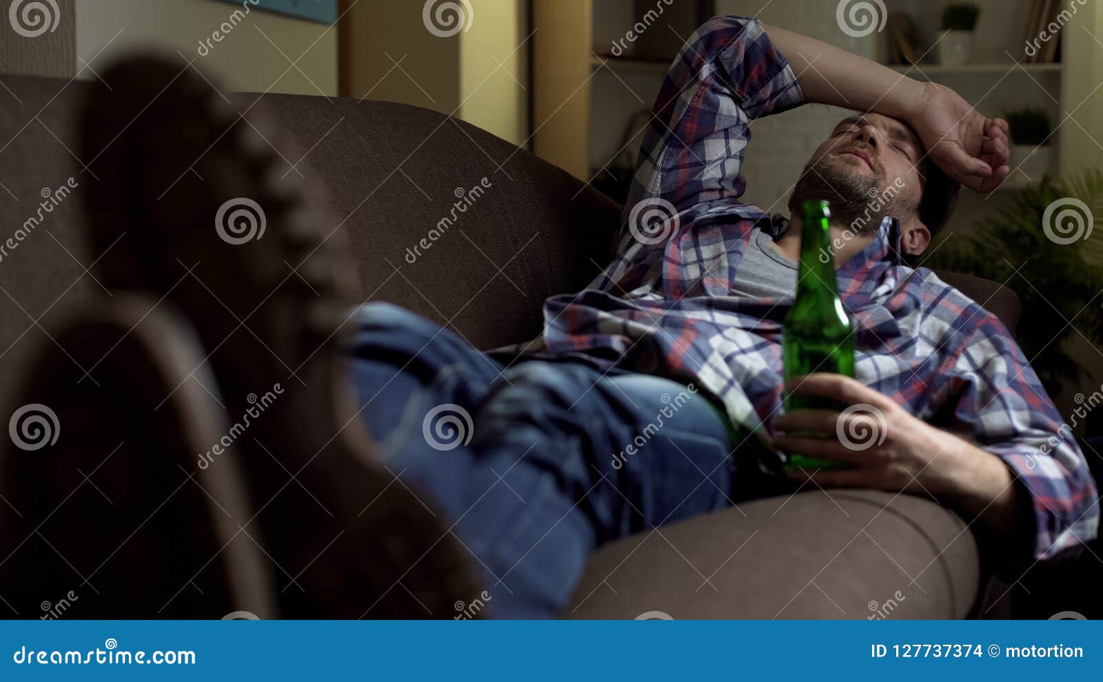 Drunk Male Sleeping on Couch with Bottle of Beer in Hand, Bad News ...