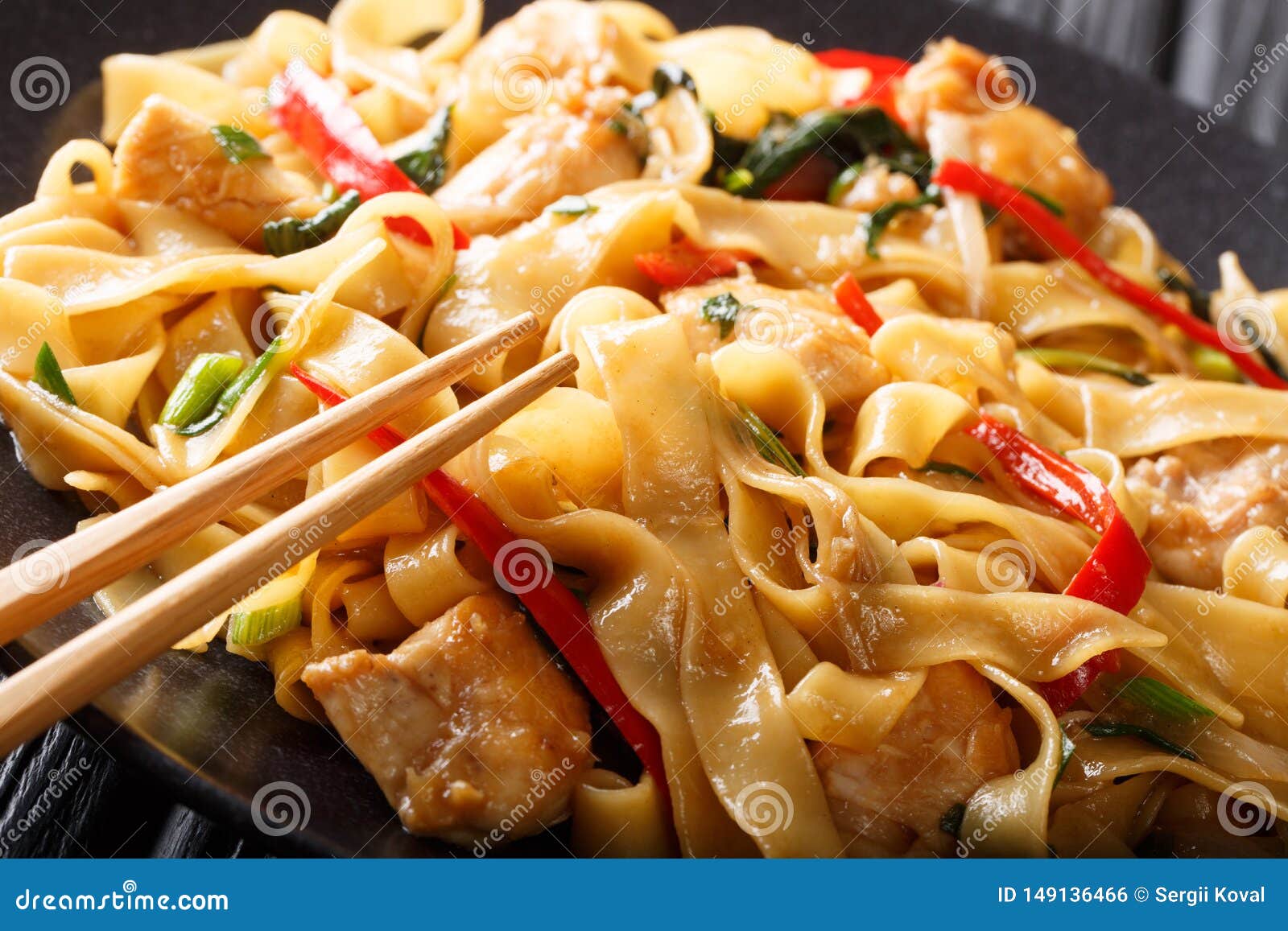 drunken noodles pad kee mao with chicken, basil, chili pepper and sauce close-up on a plate. horizontal