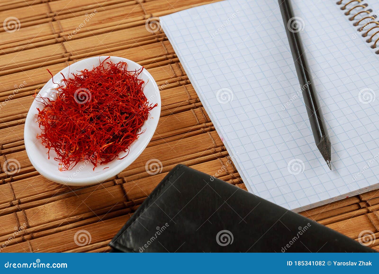 dry saffron spice on a white plate on wooden background with copybook. copy space