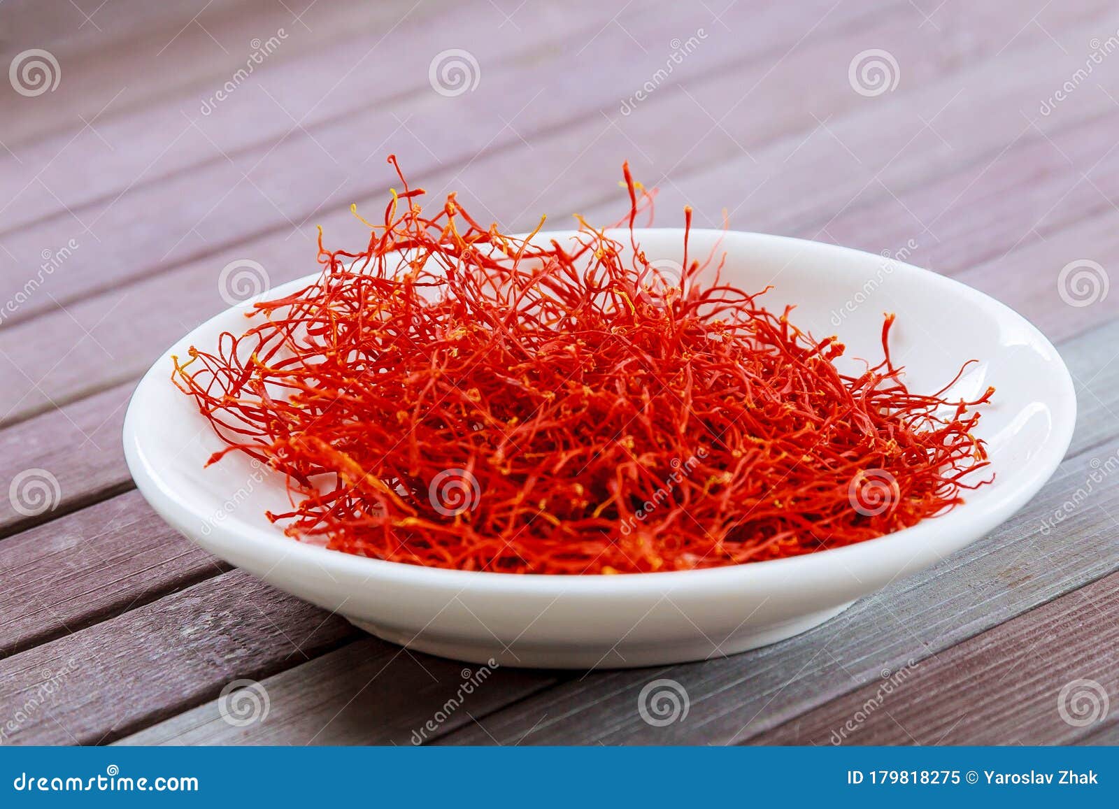 dry saffron spice on a white plate on wooden background
