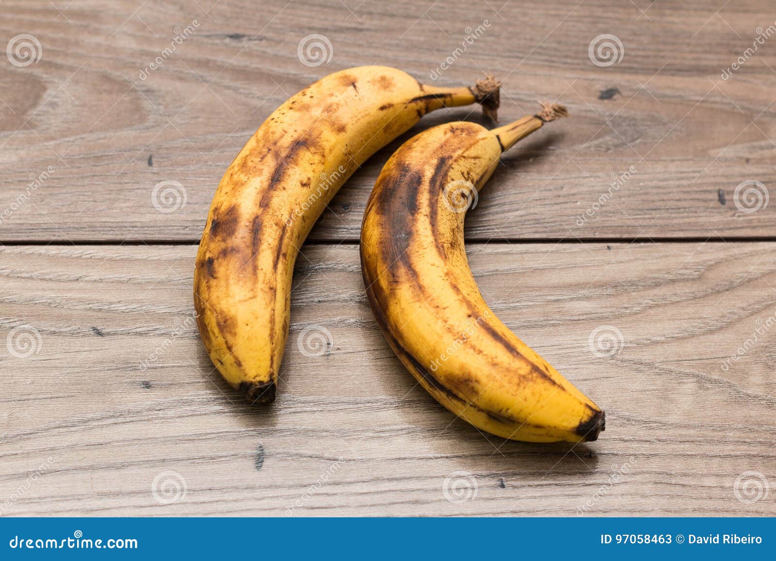 Duas bananas inteiramente maduras sobre uma tabela de madeira