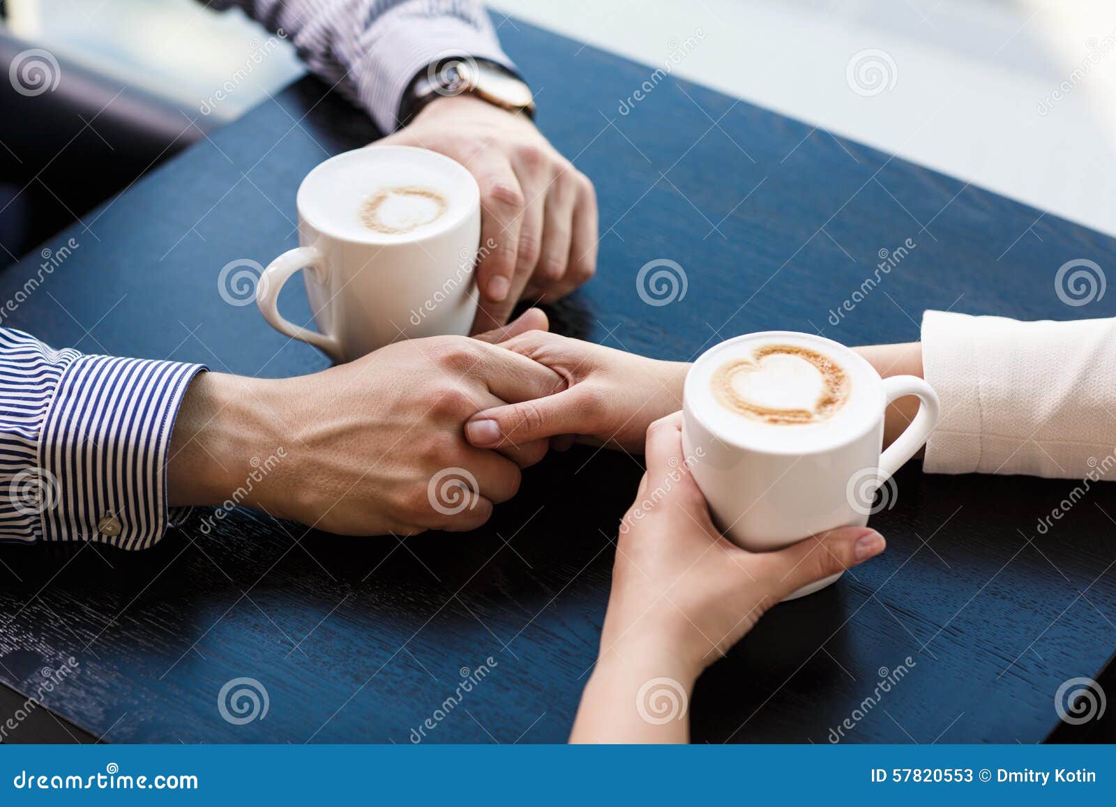 Duas chávenas de café. Mãos na tabela que guarda xícaras de café