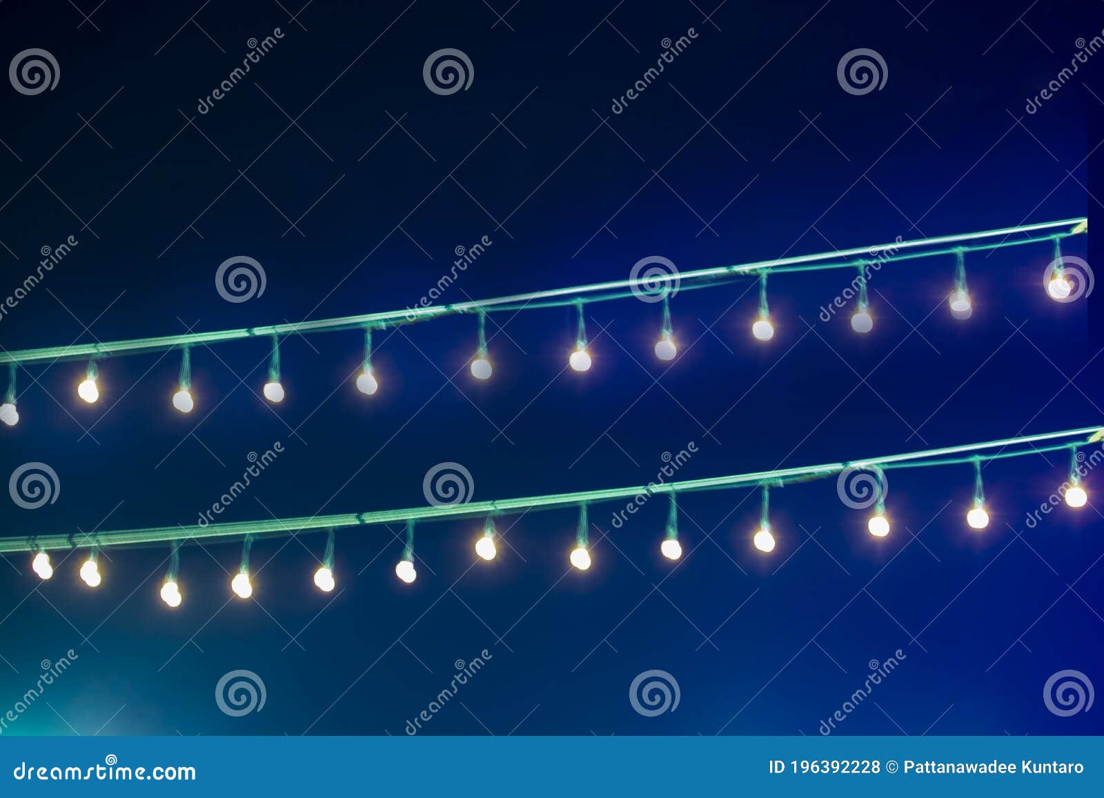 Duas linhas de movimento da cabeça da ampola multiplicadas sobre fundo azul em pé na fila. Duas linhas de movimento da cabeça da ampola multiplicadas sobre fundo azul que se encontra sobre uma luz em linha na noite