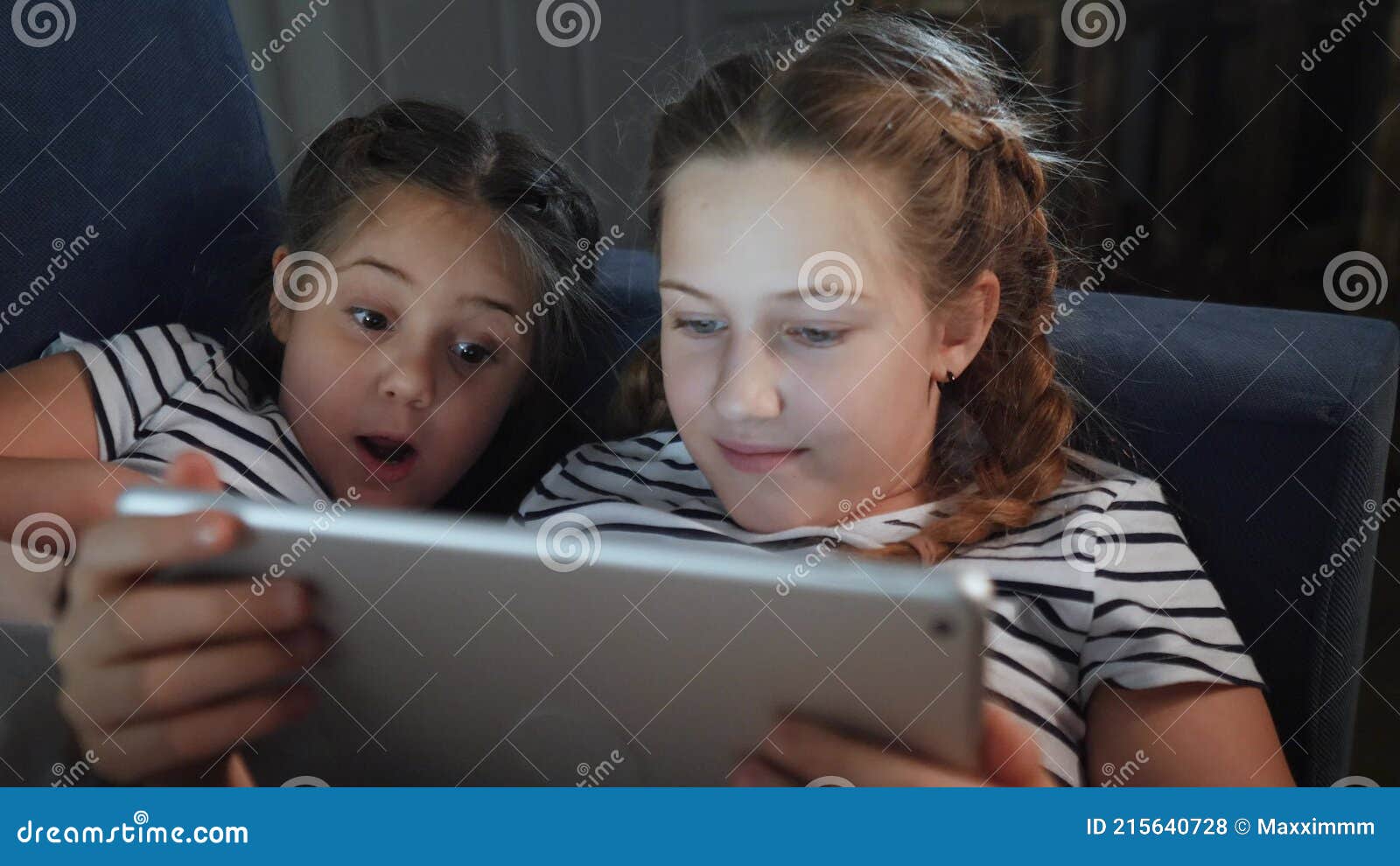 Duas Meninas No Sofá à Noite Com Um Tablet Digital. Jogos Online