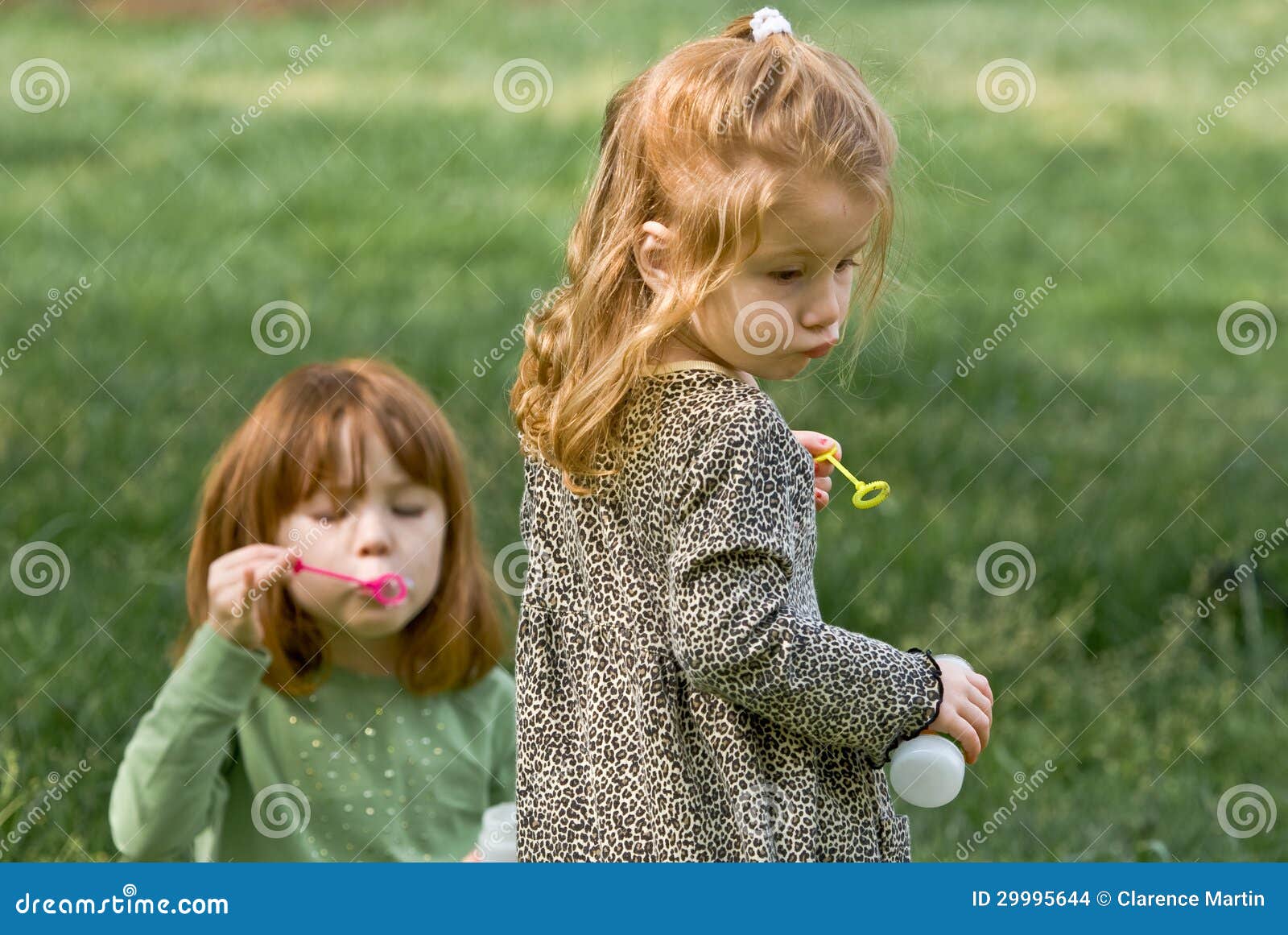 Duas raparigas que fundem bolhas e que têm o divertimento em uma tarde adiantada da mola.