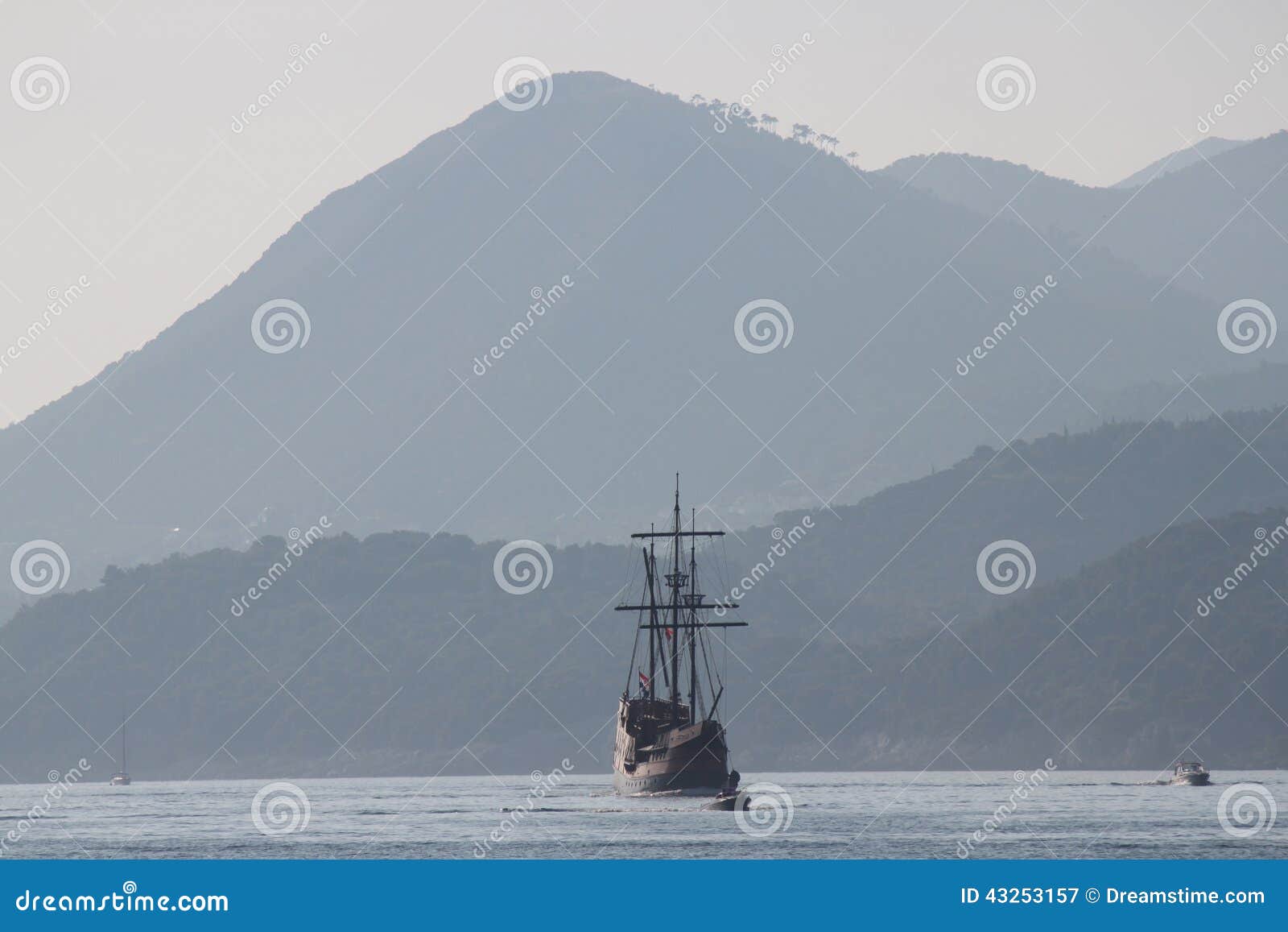 Dubrovnik, Croácia (barco do pirata & montanhas). Pirateie a selagem do barco com as montanhas lisas atrás em Dubrovnik, Croácia