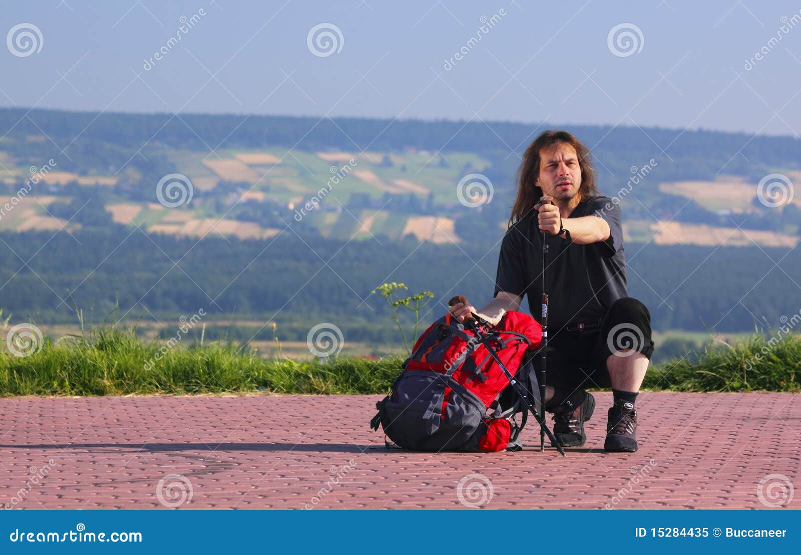 Duckender Tourist. Duckender Wanderer mit Rucksack und trekking Steuerknüppeln. Bild mit Exemplarplatz am links.