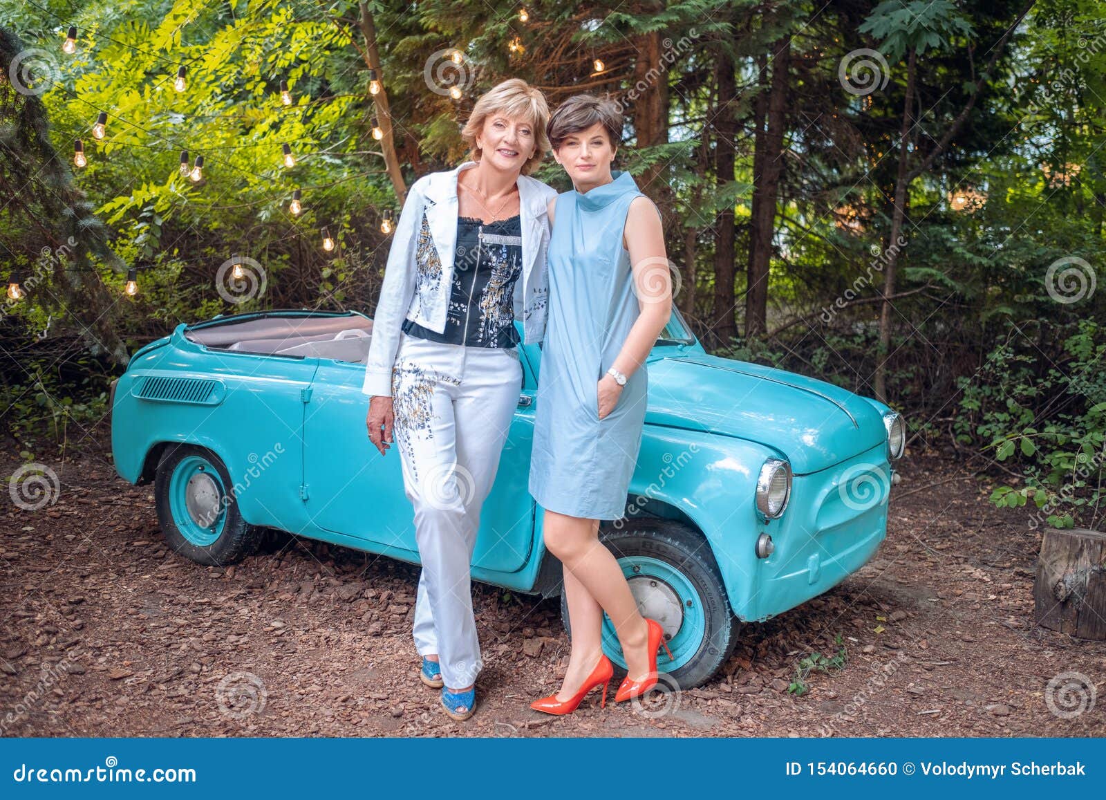 Due donne in un'automobile d'annata la madre senior felice e la figlia adulta fanno una pausa un retro convertibile all'aperto