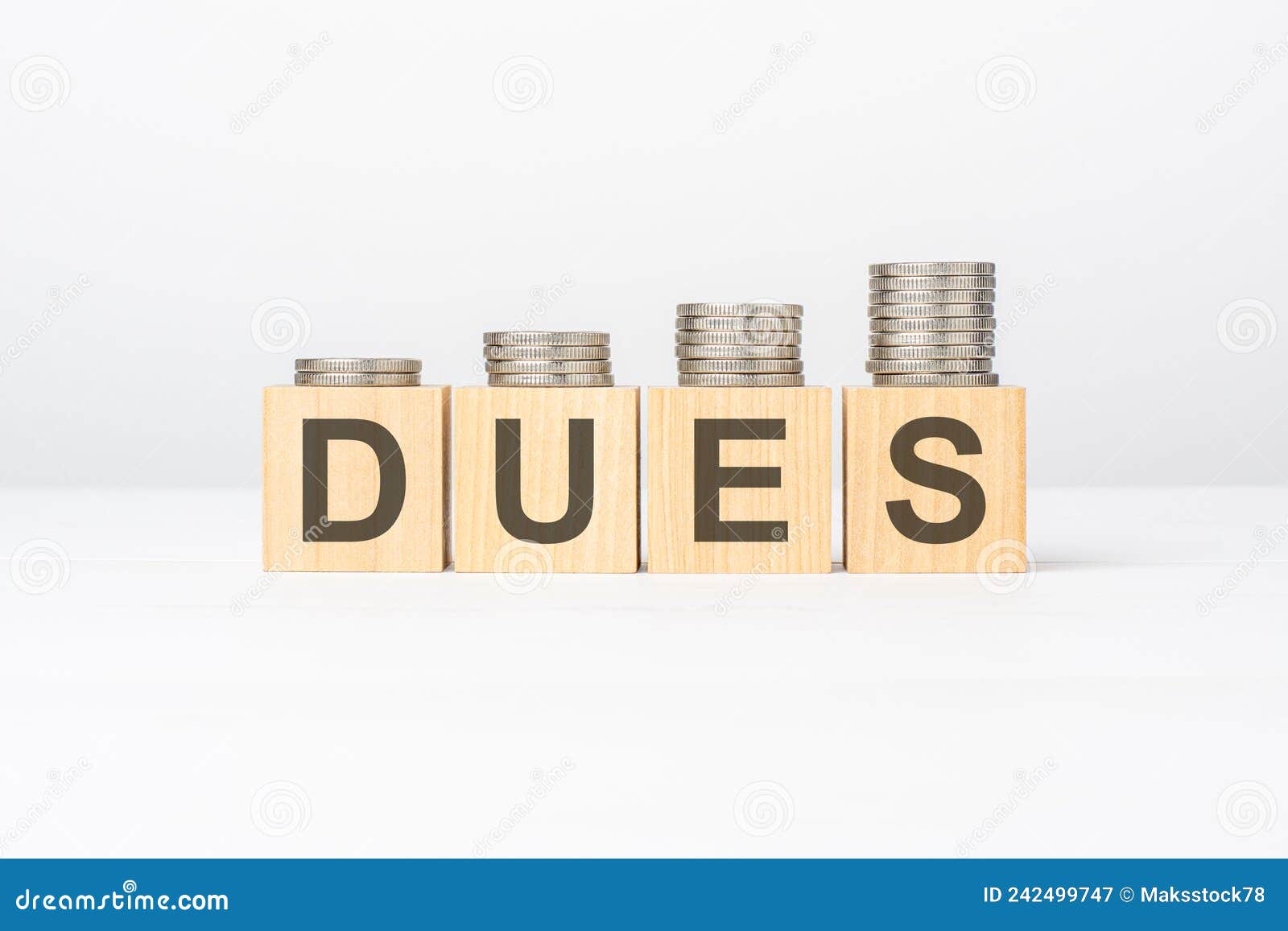 dues text written on wooden block with stacked coins on white background