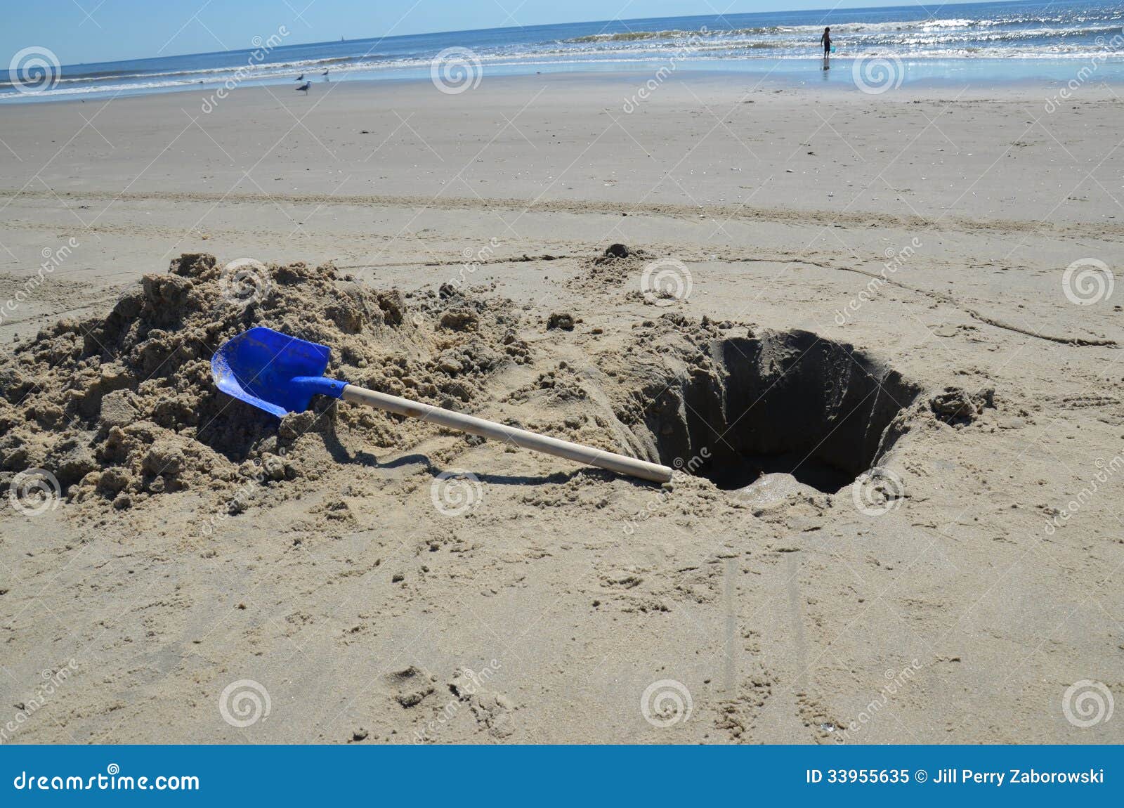 Dug Hole On The Beach With A Blue Shovel Royalty Free Stock Photo