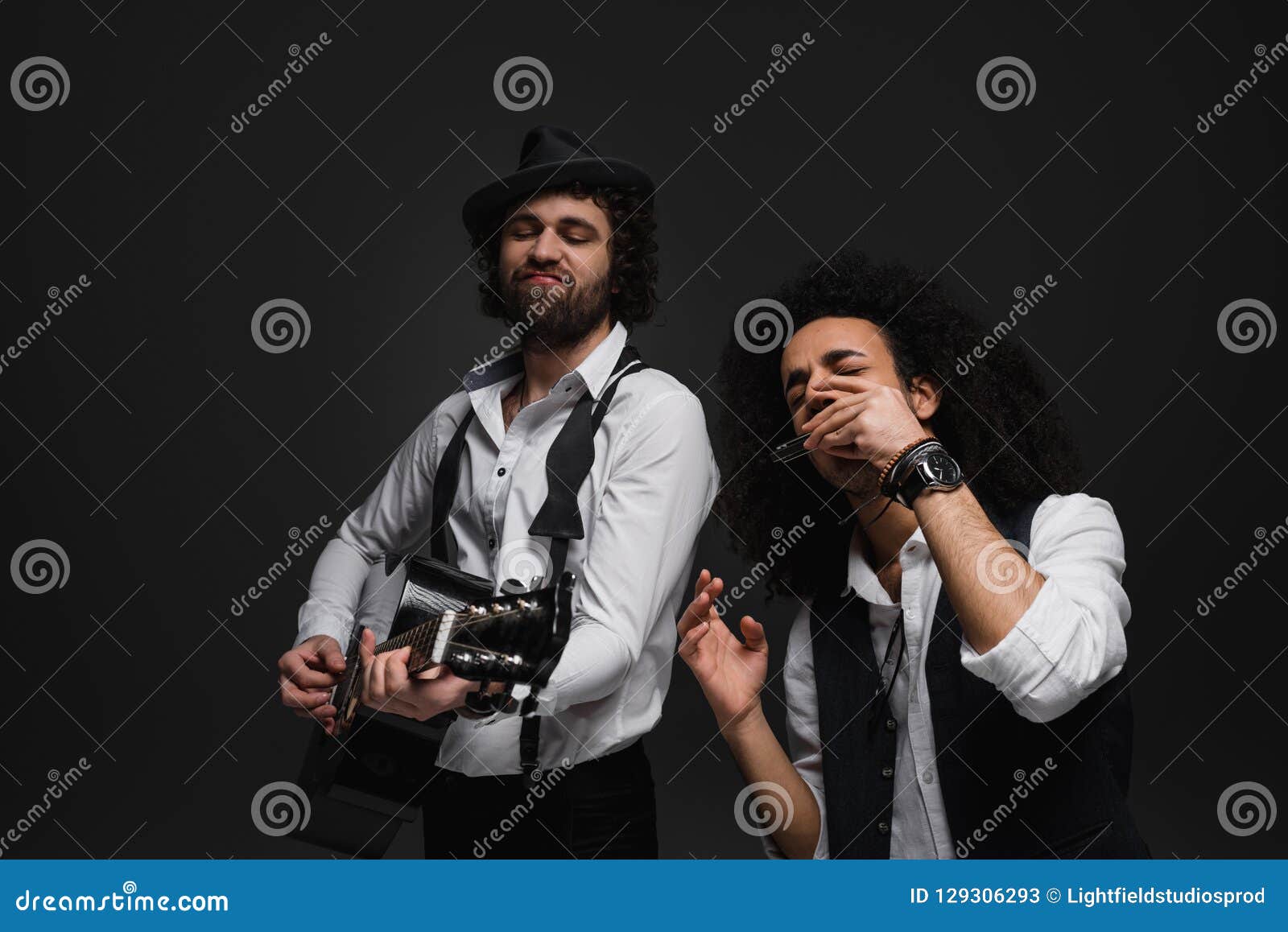 Duo des musiciens expressifs jouant la guitare acoustique et l'harmonica sur le noir