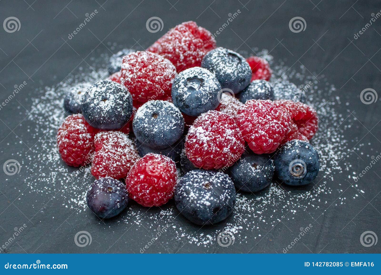 A Dusting of Icing Sugar on Blueberries and Raspberries on a Grey Slate