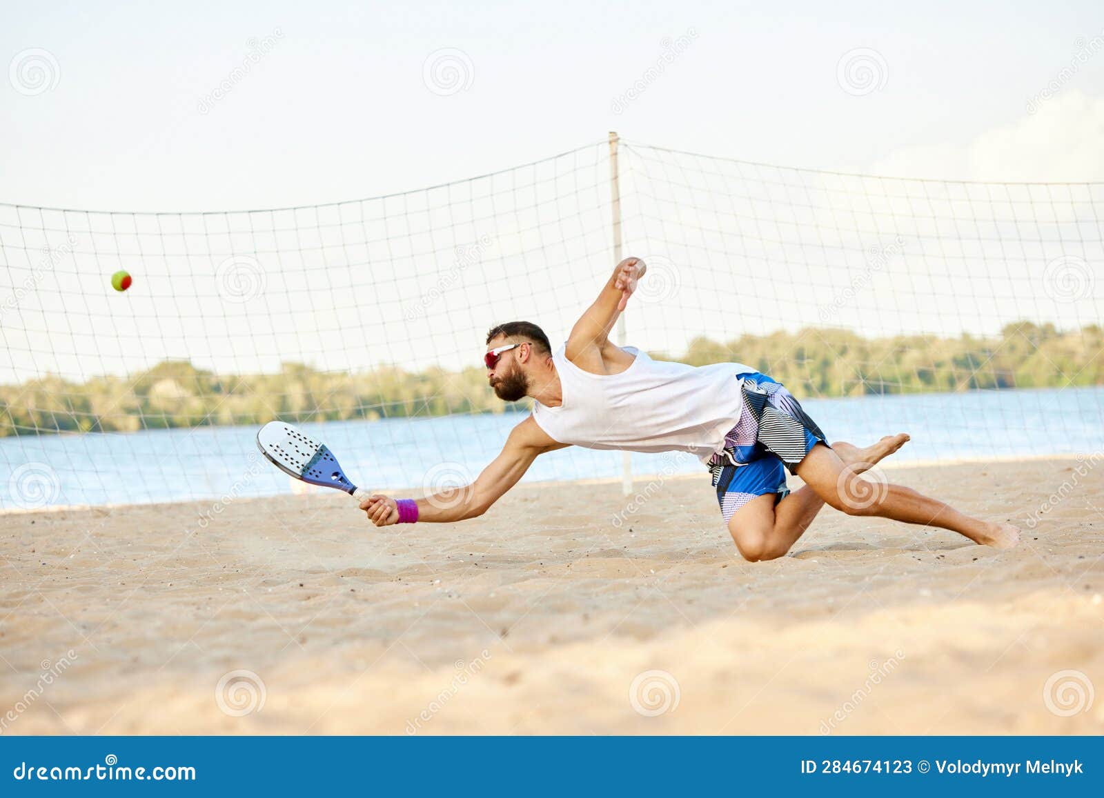 Dynamic Image of Young Man Playing Beach, Paddle Tennis, Hitting Ball