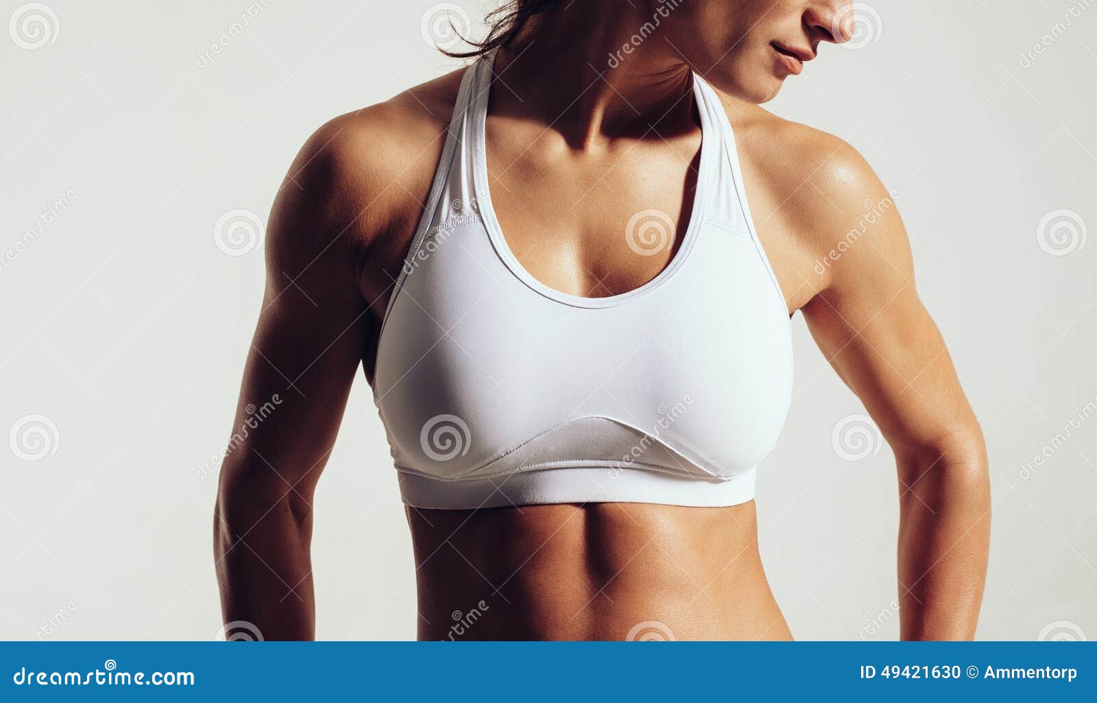 Portret dysponowana kobieta w sporta staniku z mięśniowym ciałem przeciw popielatemu tłu Zakończenia studia strzał żeński sprawność fizyczna model w sportach jest ubranym