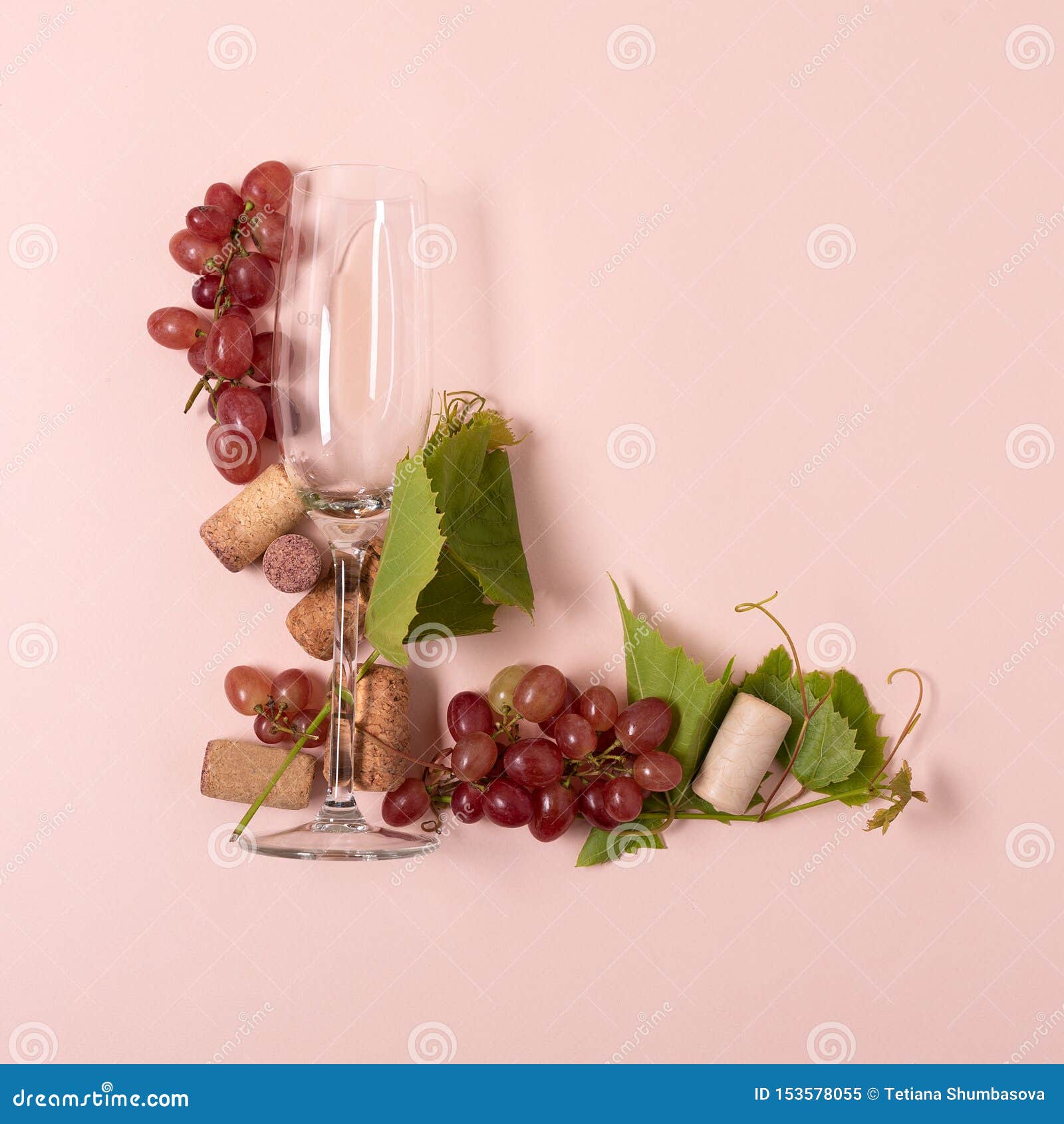 E 信件l做了有的玫瑰的葡萄酒杯和白酒 葡萄 说谎的叶子和的黄柏在桃红色背景 库存图片 图片包括有粉红色 字法
