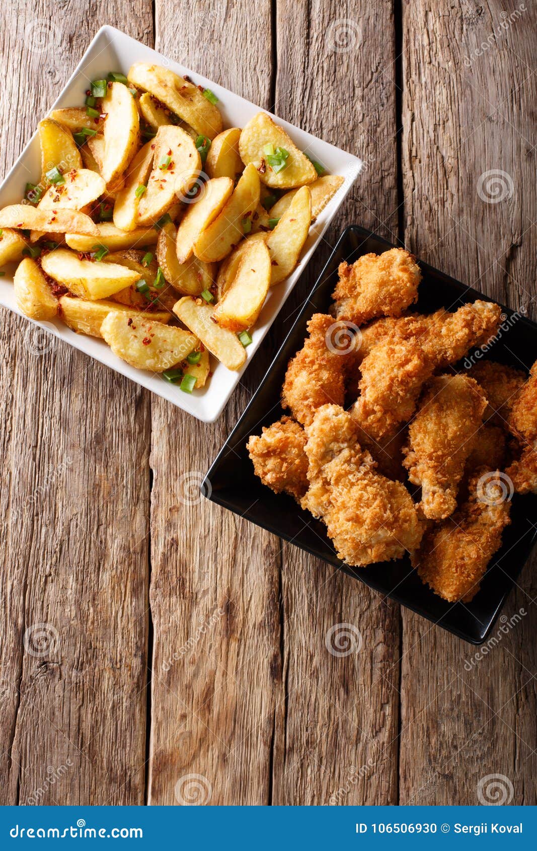 Fried Chicken Wings in Bread Crumbs and Potato Wedges Close Up. Stock