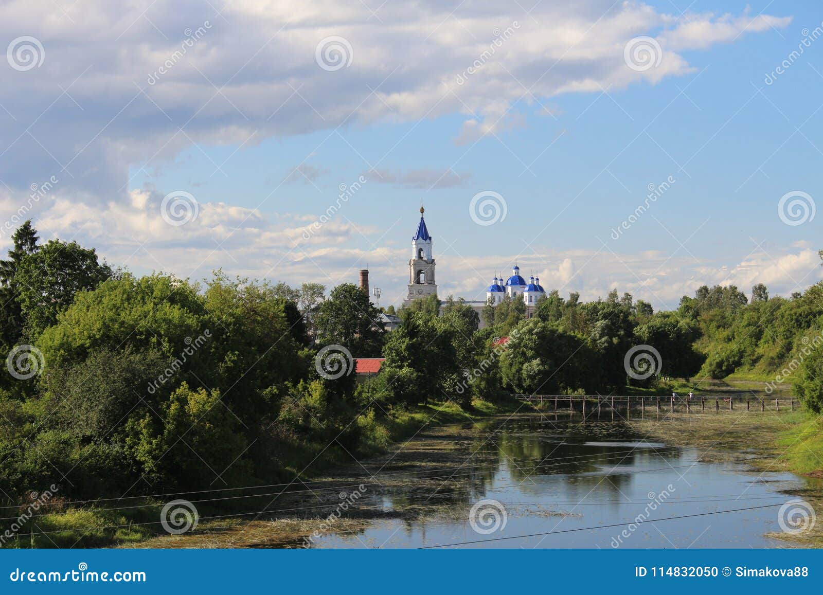 Voskresensky Cathedral among green trees against the blue sky, the city of Kashin, Tver region. The Voskresensky Cathedral among the summer green trees, near the river against the blue sky, the city of Kashin, Tver region